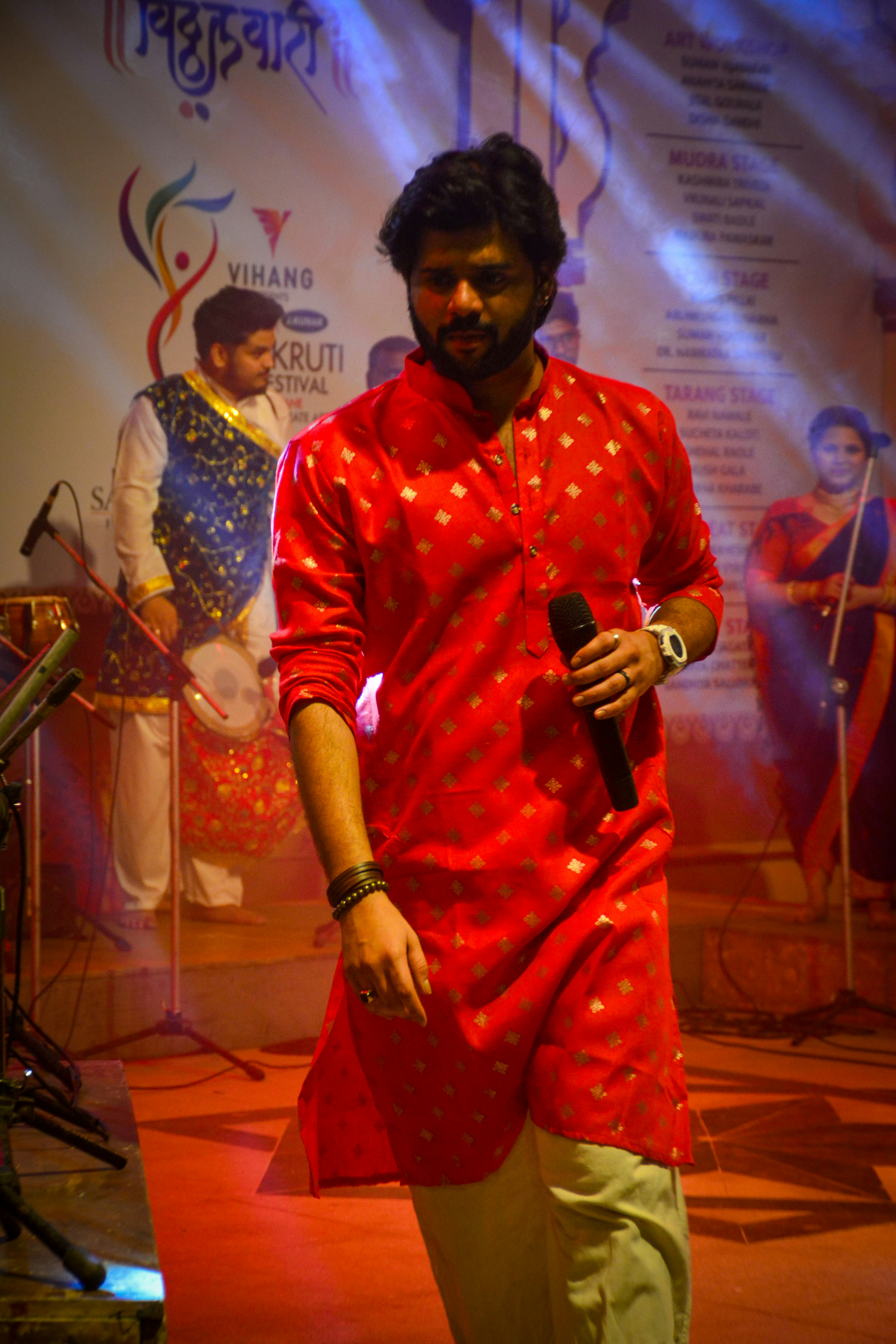 Man in red kurta holding microphone on stage