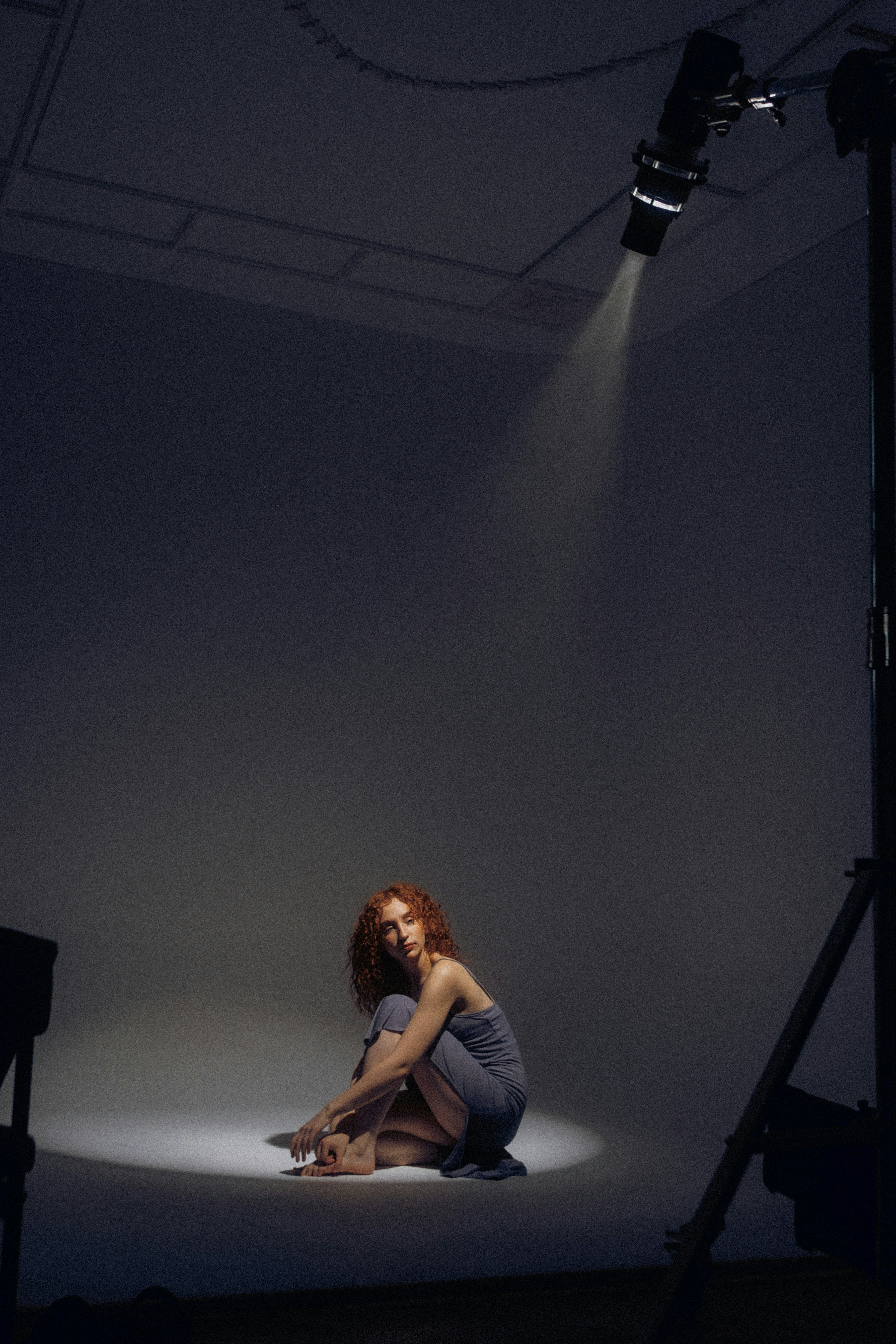 Eine Frau mit roten Haaren sitzt unter einem Scheinwerfer.