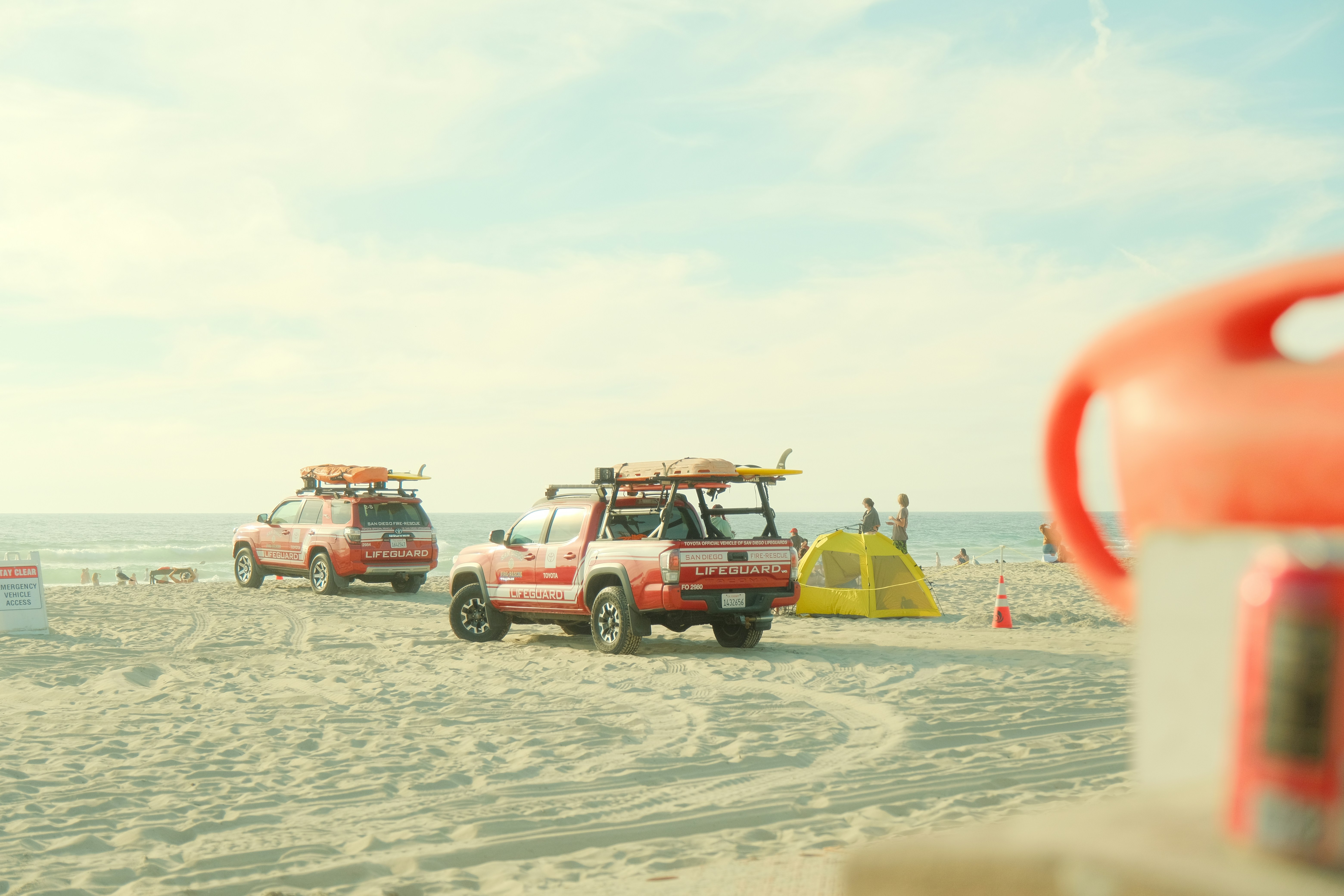 Lifeguard vehicles parked on a sandy beach near ocean.