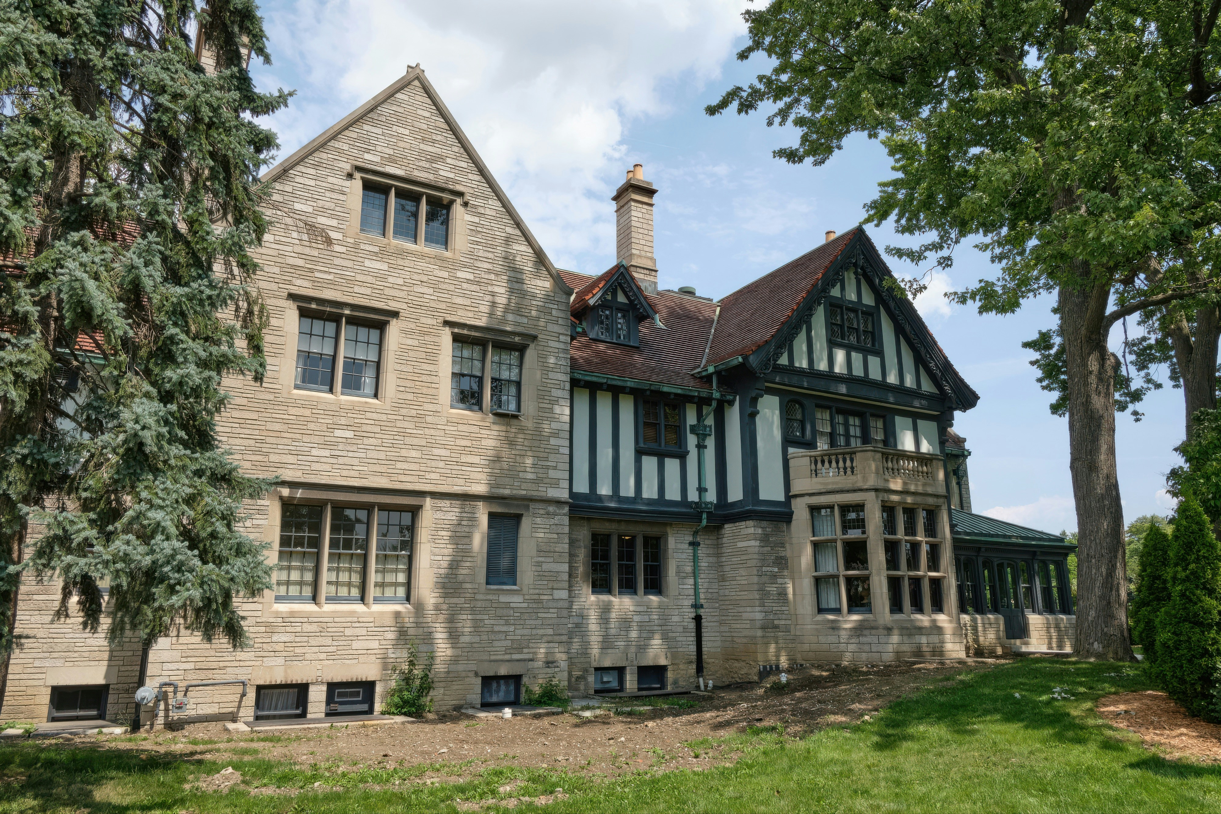 Una gran casa de piedra de estilo Tudor con árboles.