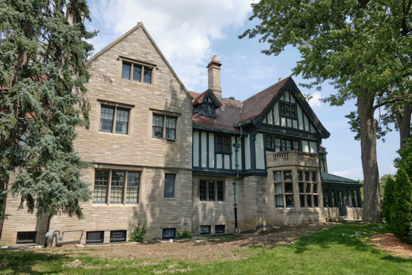 Historic stone manor with arched windows and mature landscaping