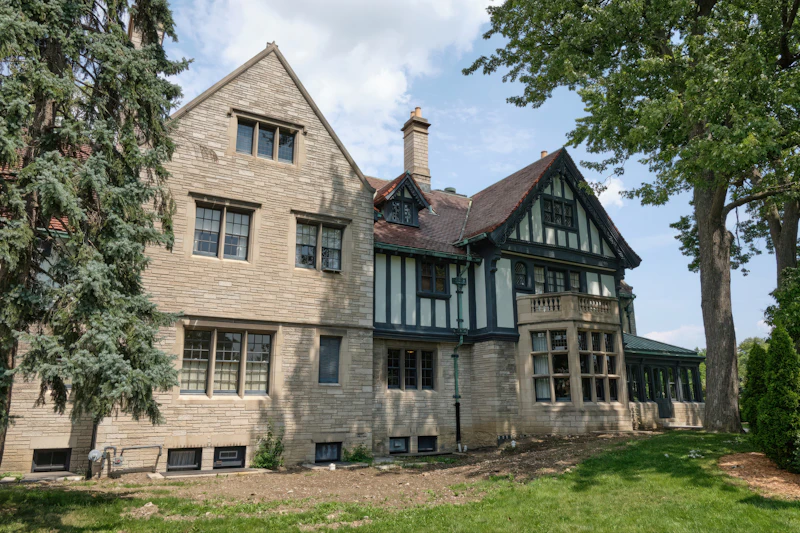 Historic stone manor with arched windows, terraces, and mature landscaping