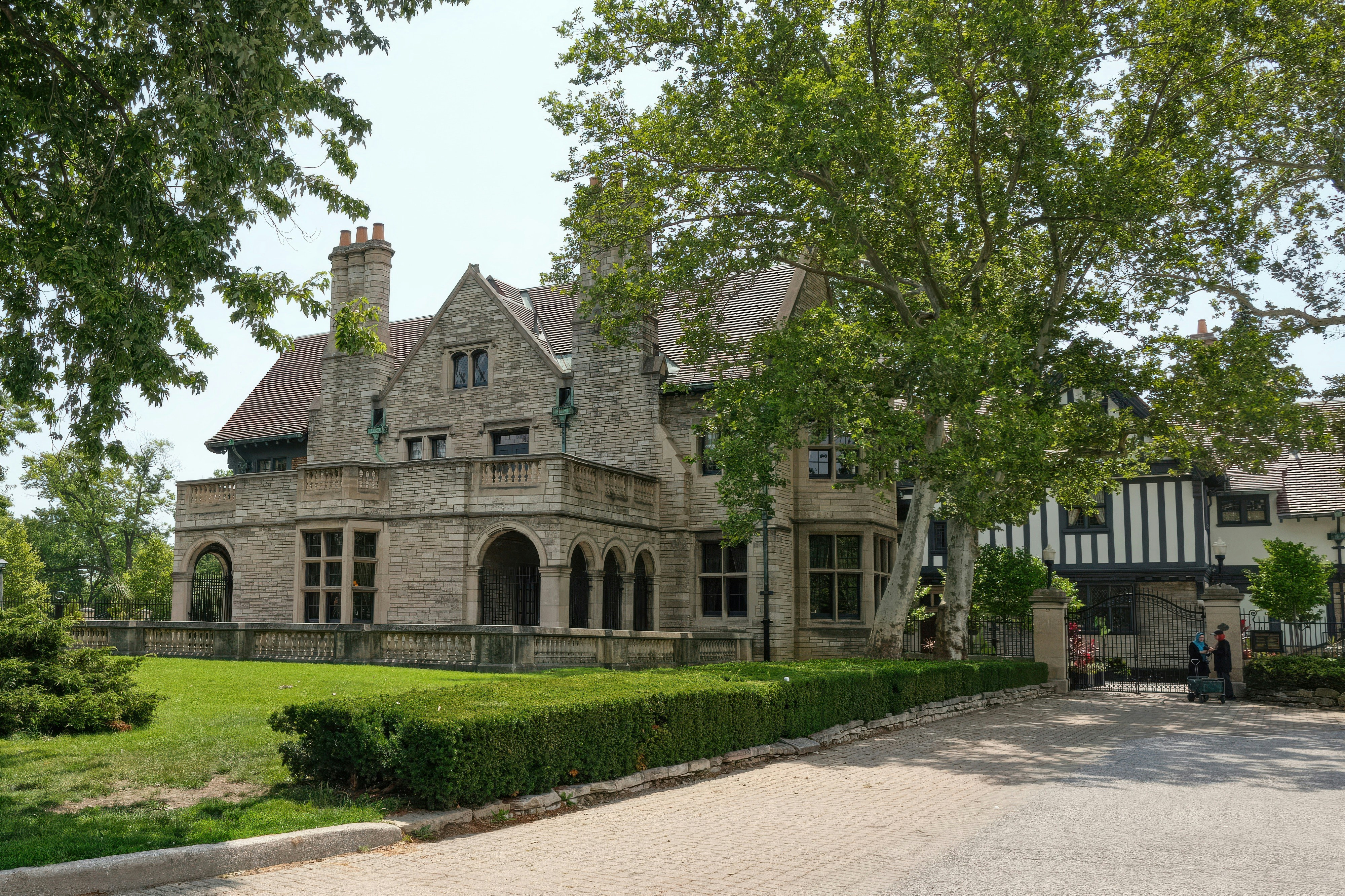 A large stone mansion with manicured lawns and trees.