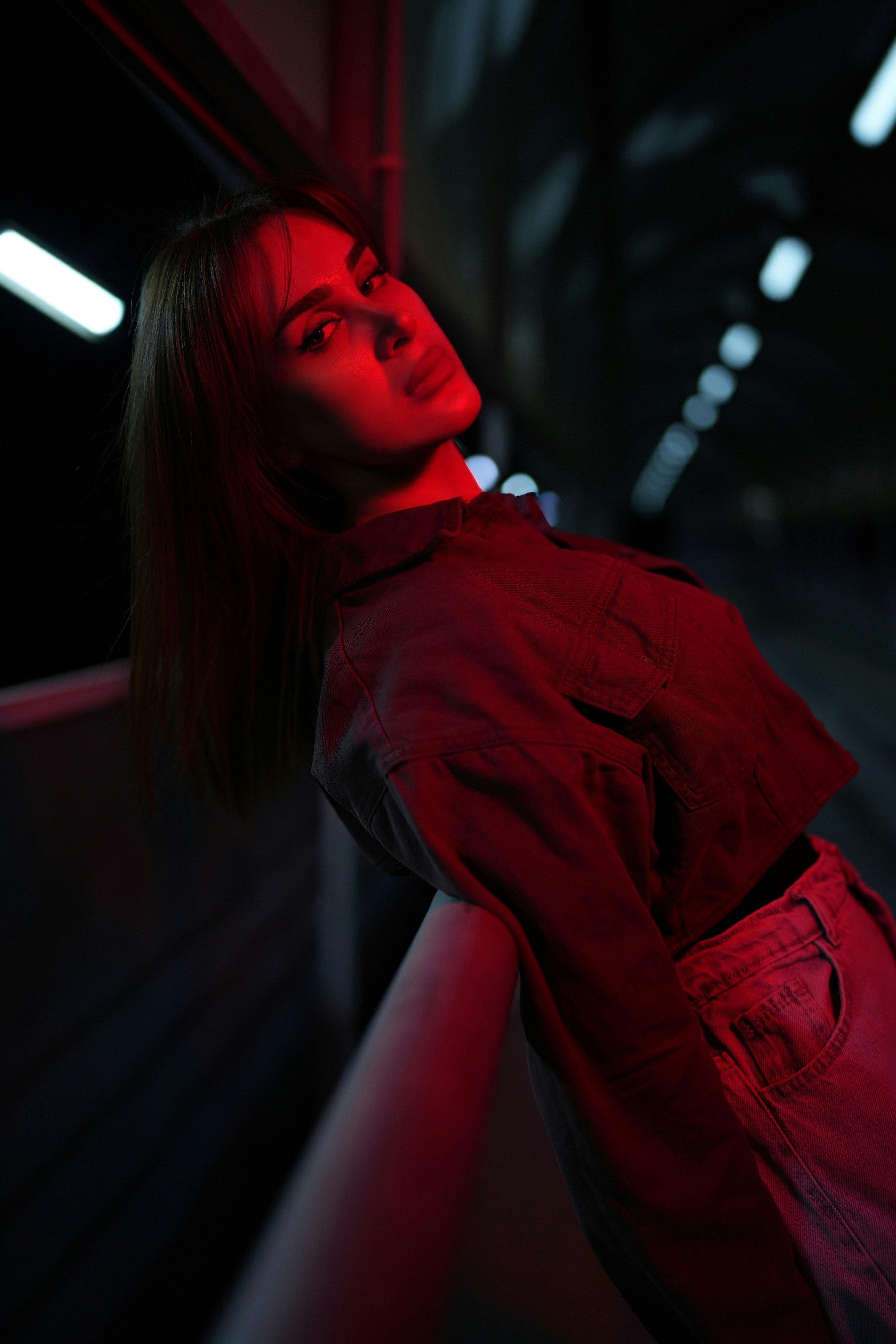 Femme illuminée par une lumière rouge dans un cadre sombre