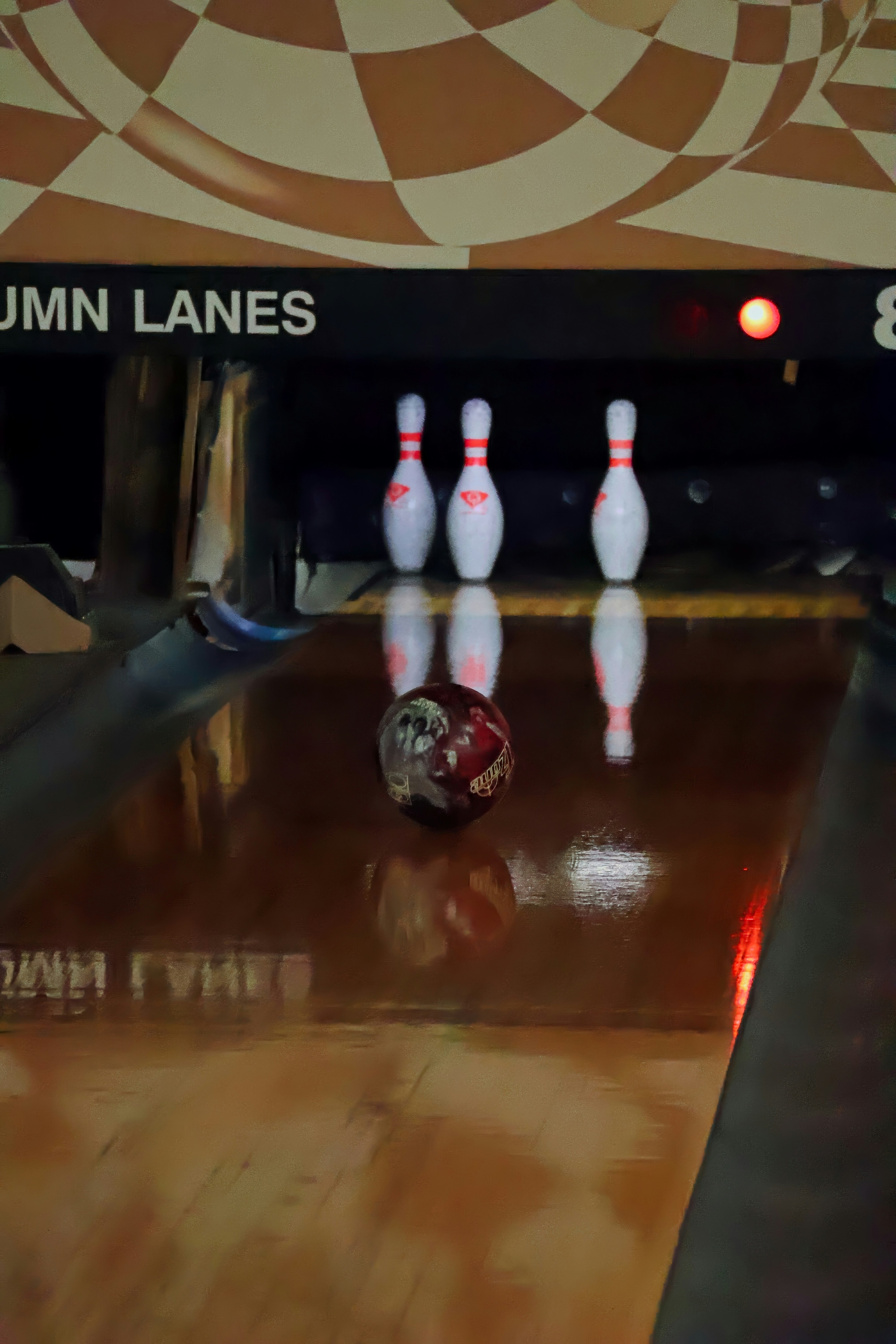 Bowling ball rolling towards pins on polished lane
