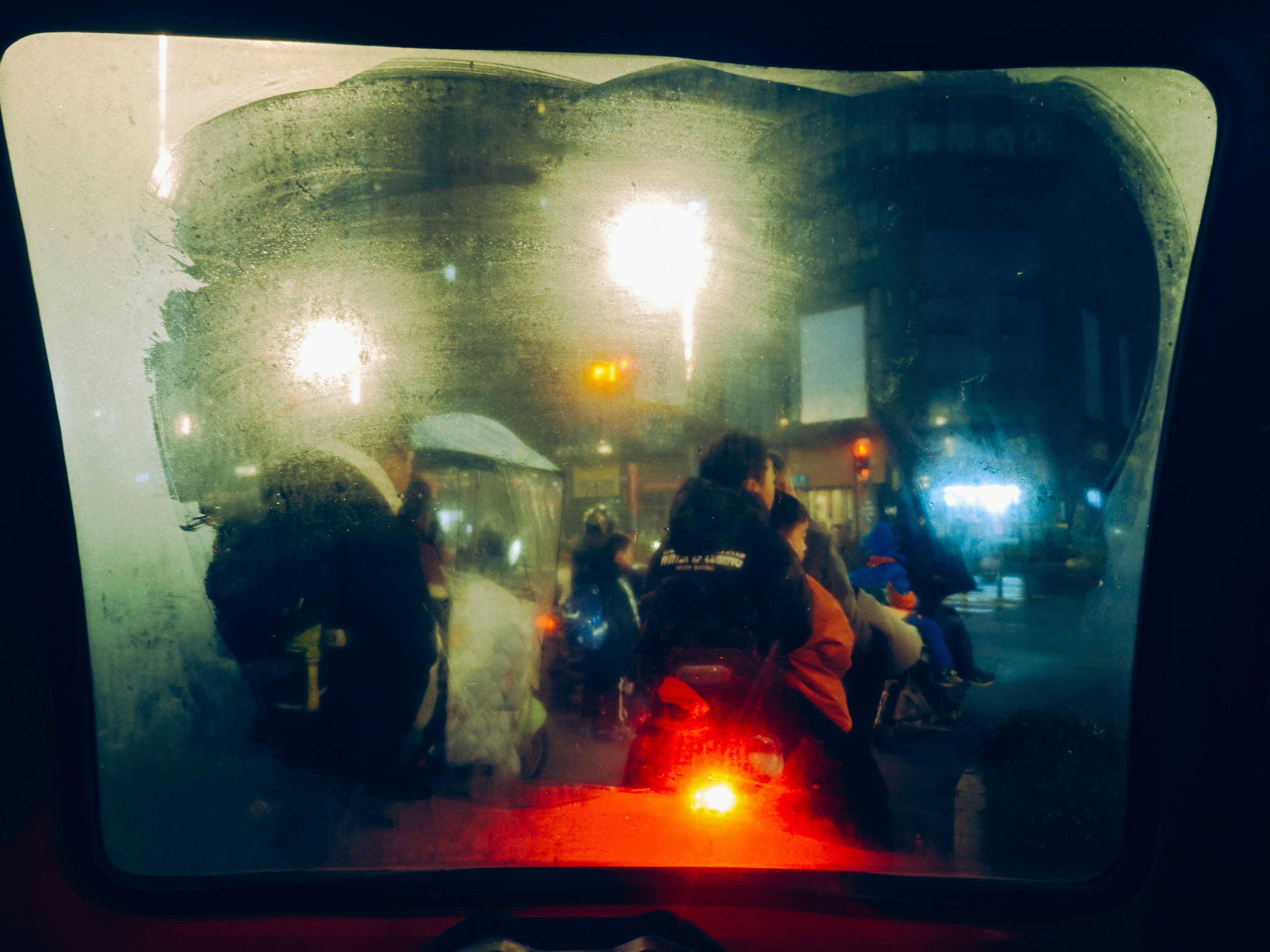 Vista a través de un parabrisas mojado por la noche con el tráfico.