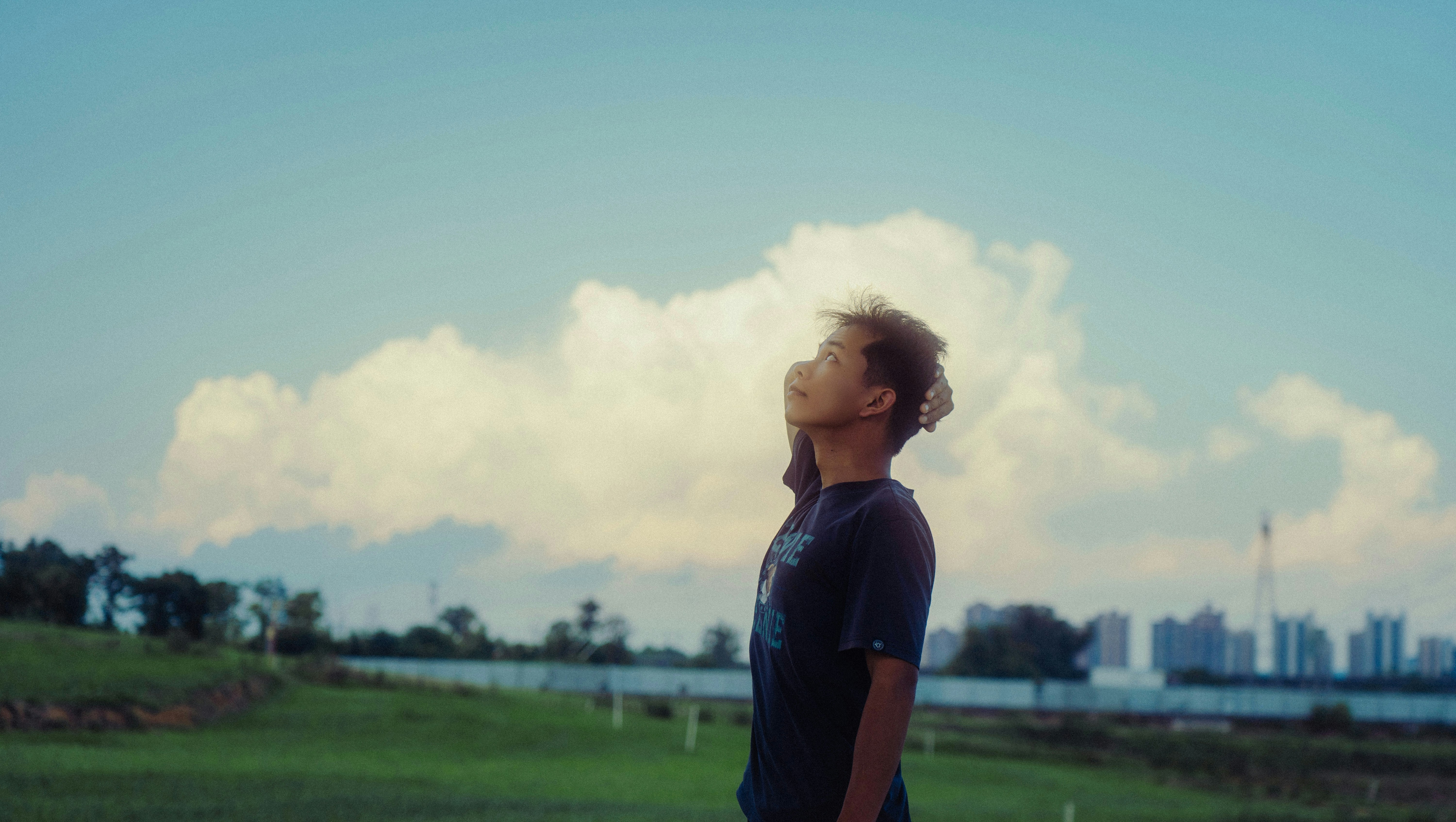 Joven mirando hacia nubes esponjosas en el cielo