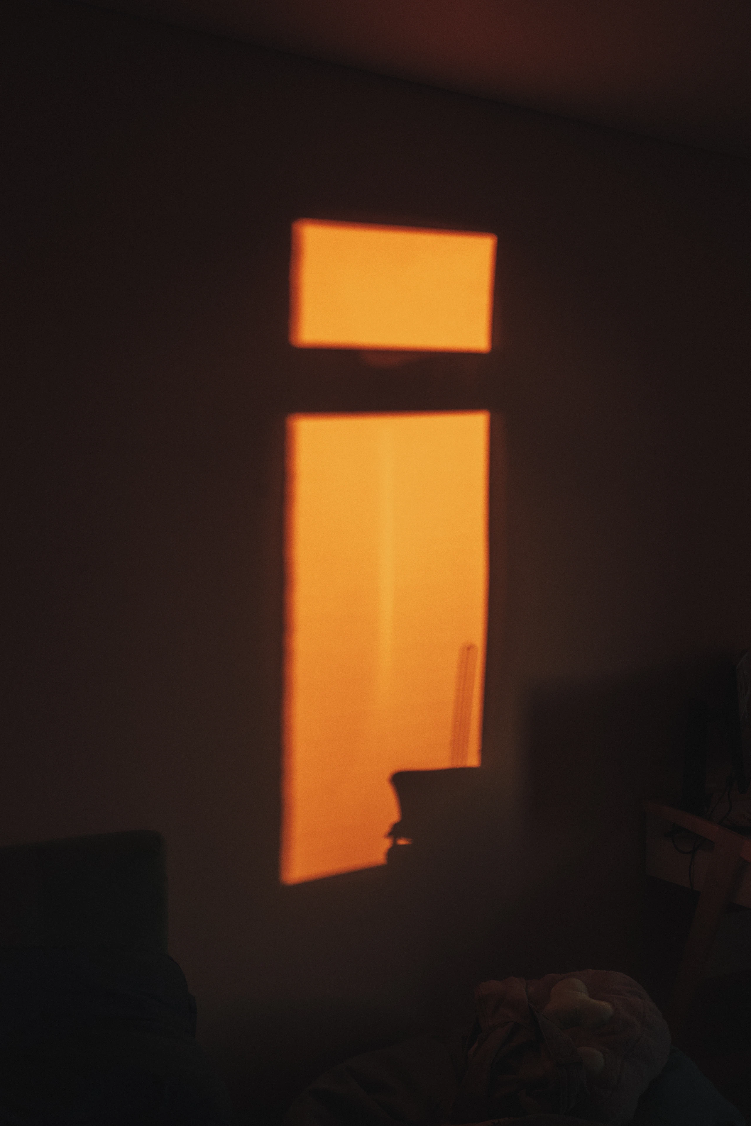 The last orange light falling through a window onto a darkened wall.