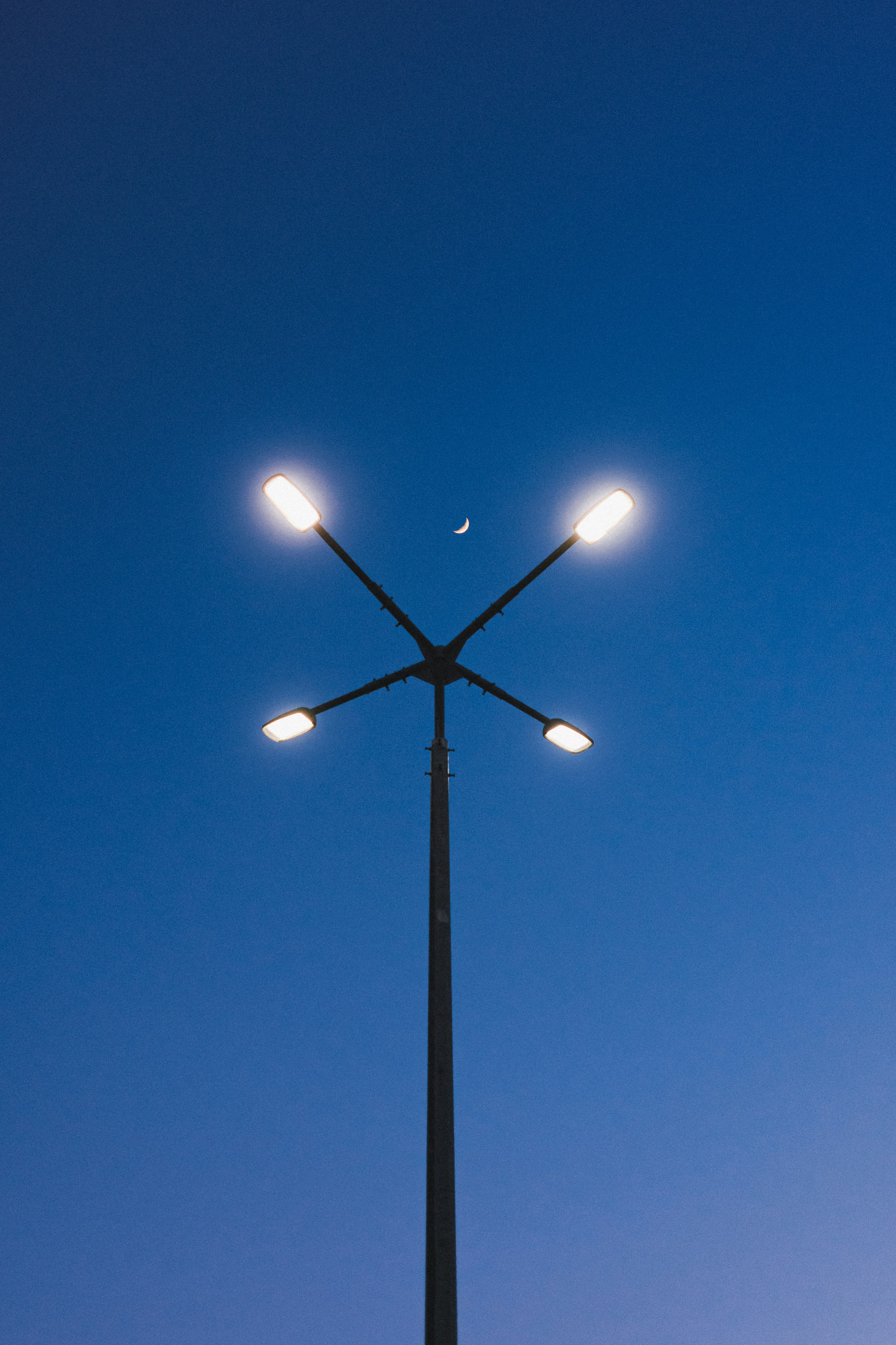 Streetlight with crescent moon in clear blue sky