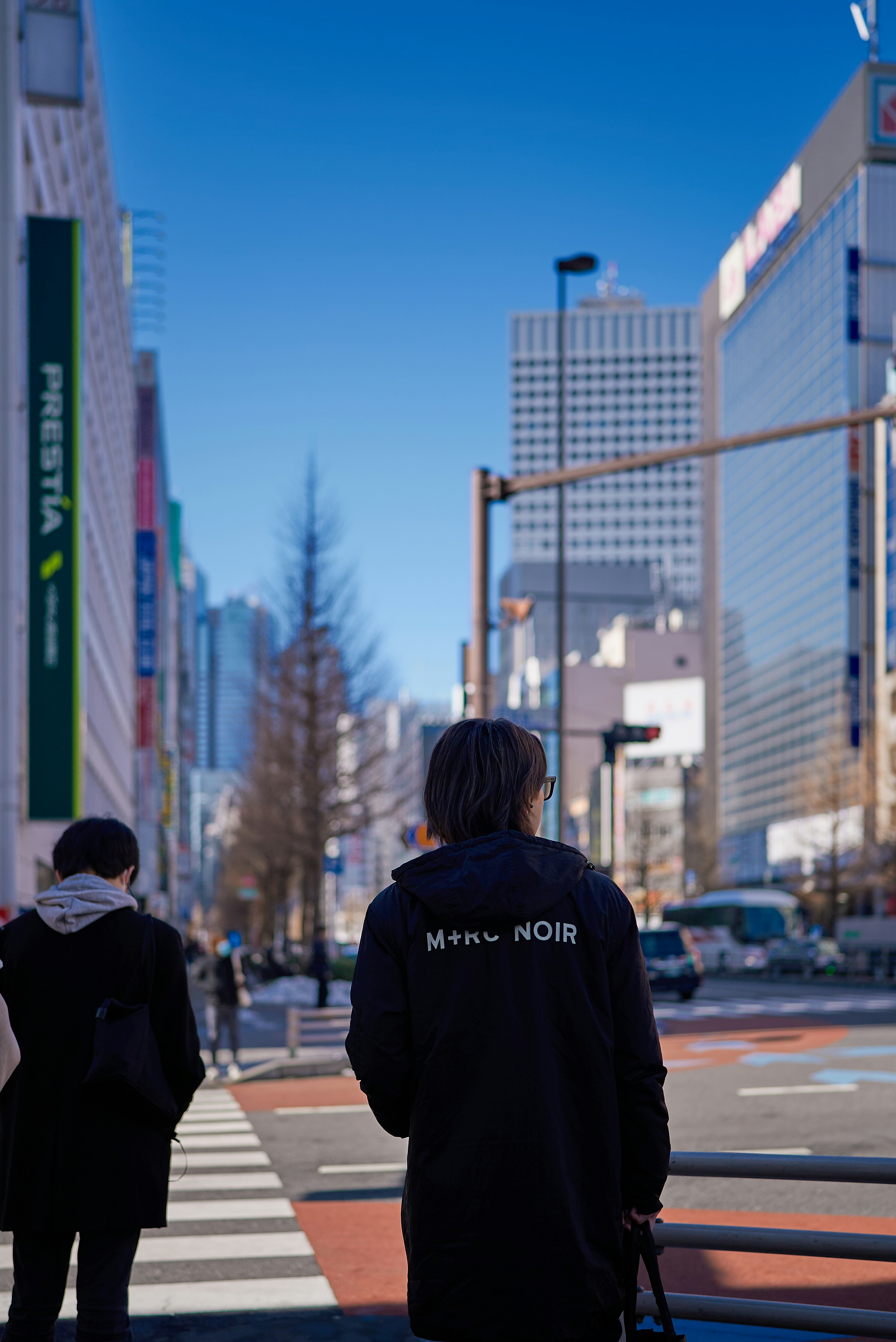 People walking on a city street with tall buildings.