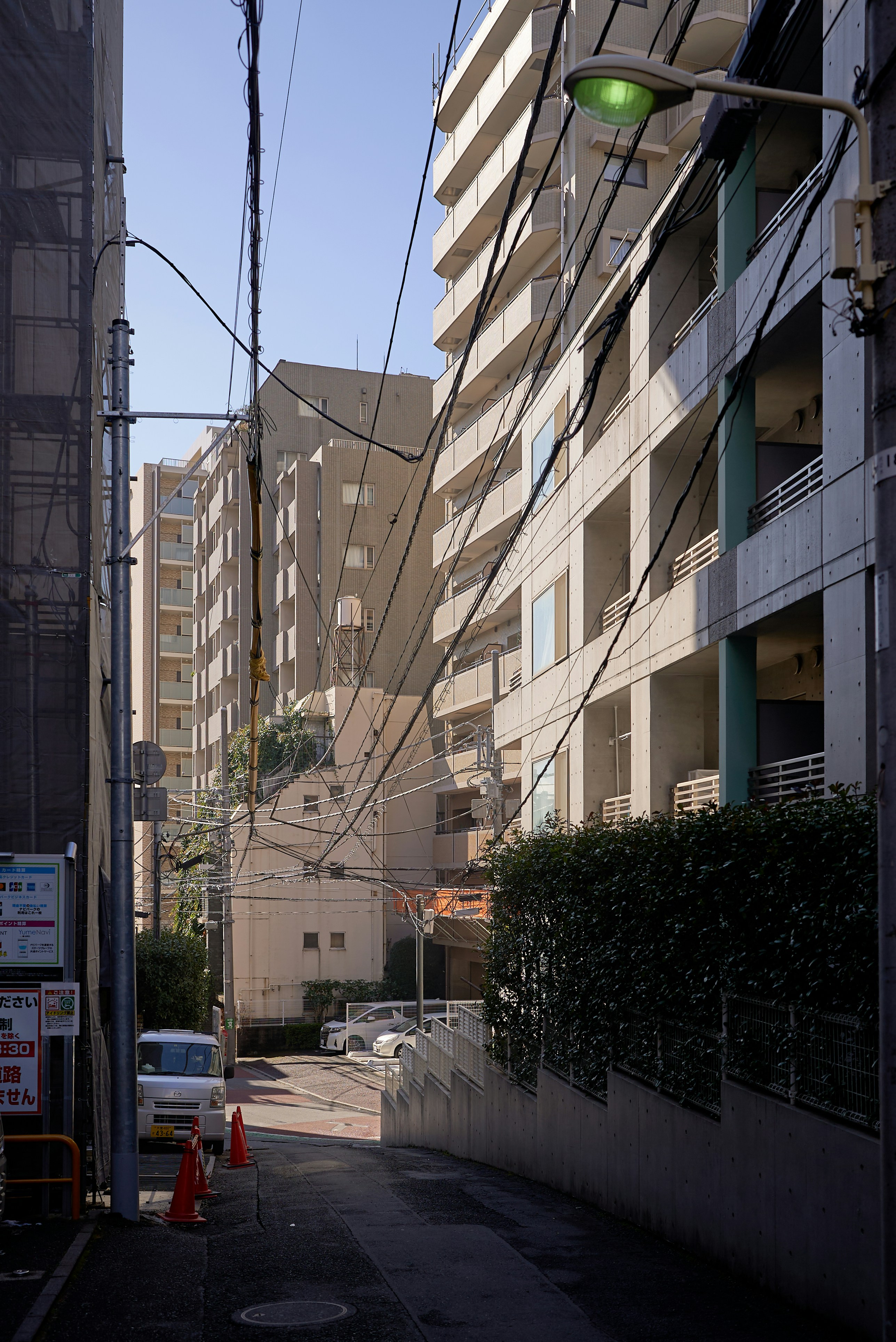 Narrow street between apartment buildings with power lines.