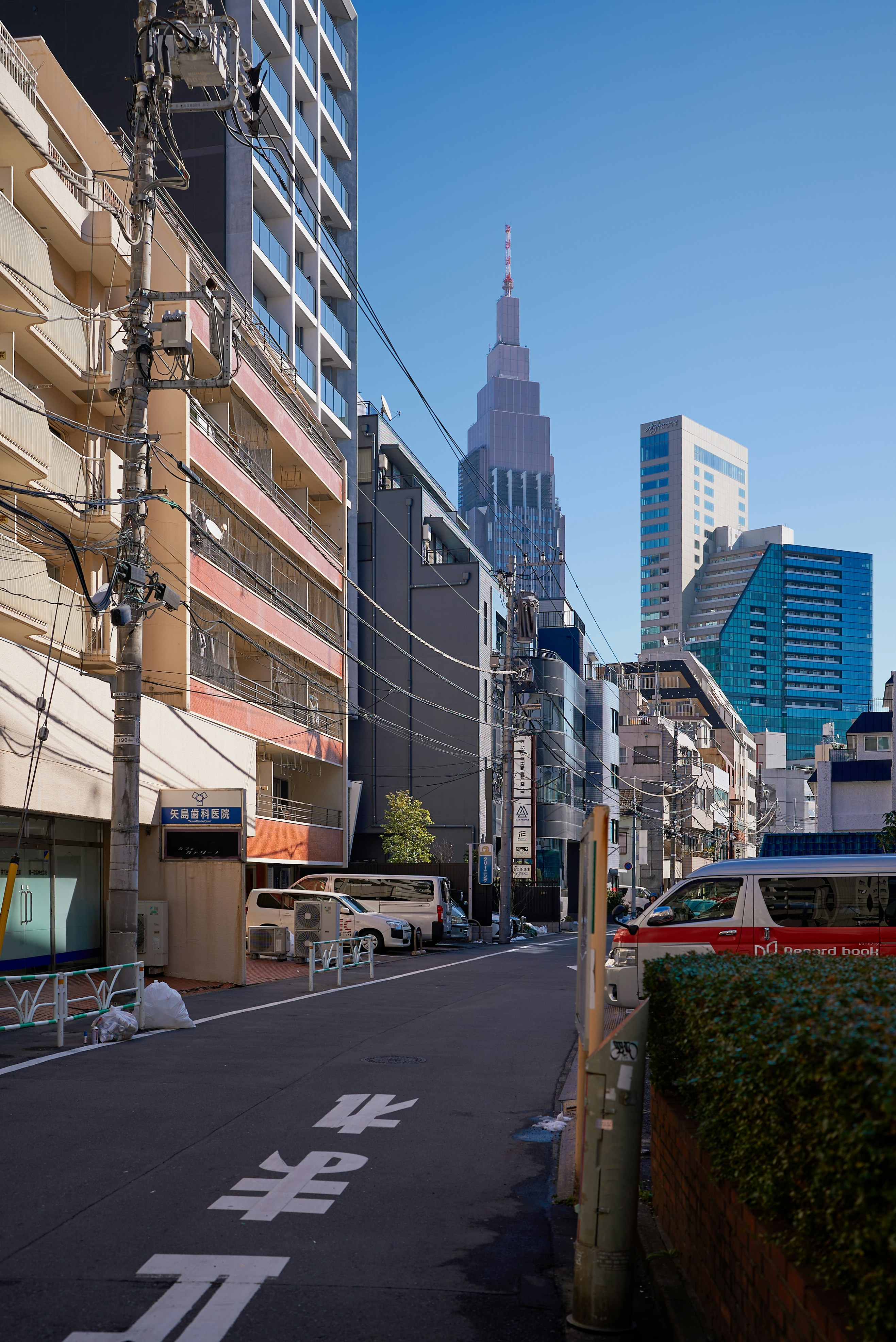 Modern city street with tall buildings and vehicles.
