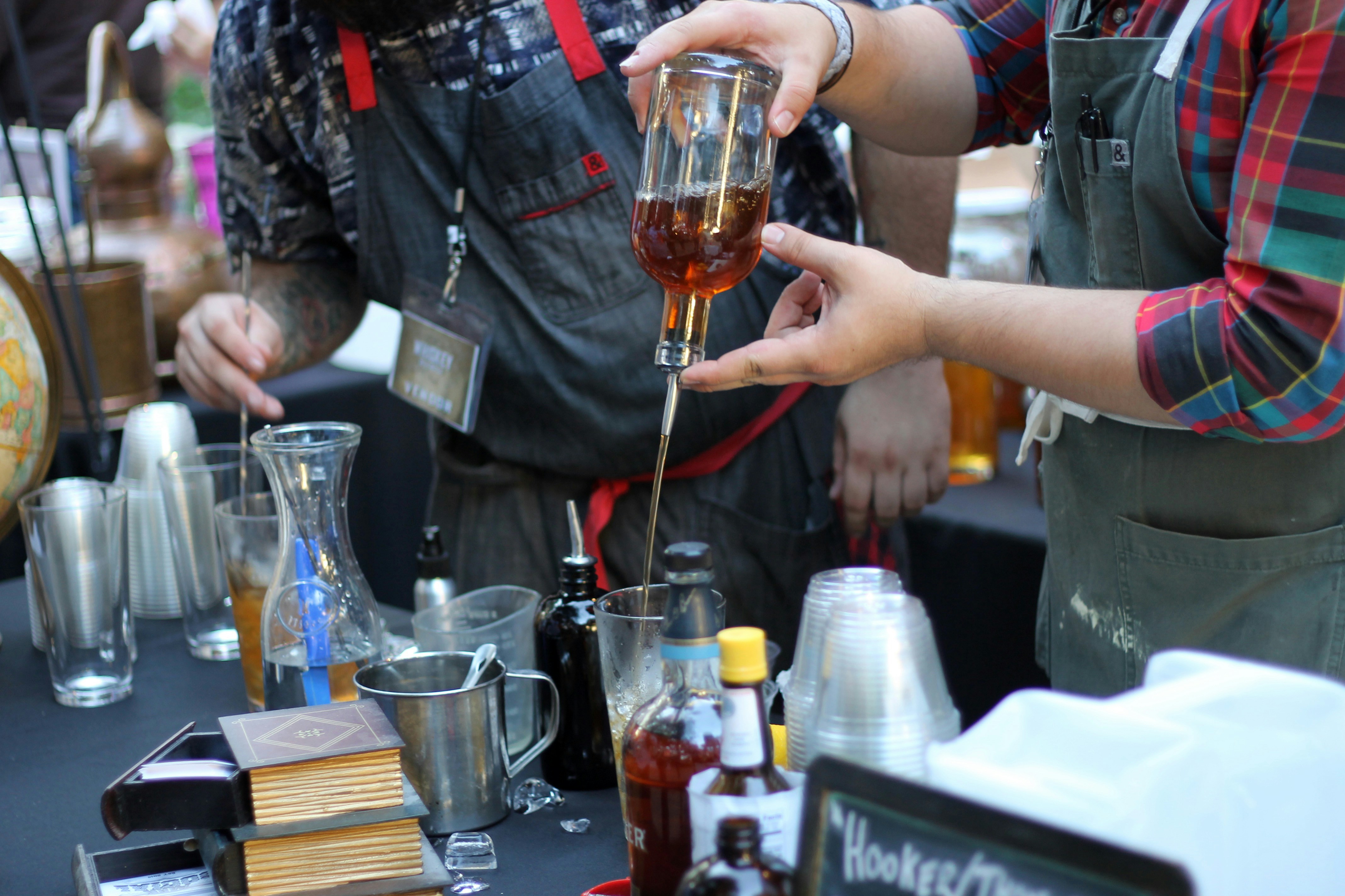 Two bartenders pouring and serving drinks side by side at a busy event bar