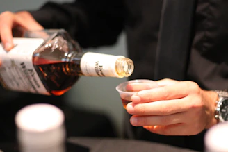 Pouring amber liquid from bottle into small cup