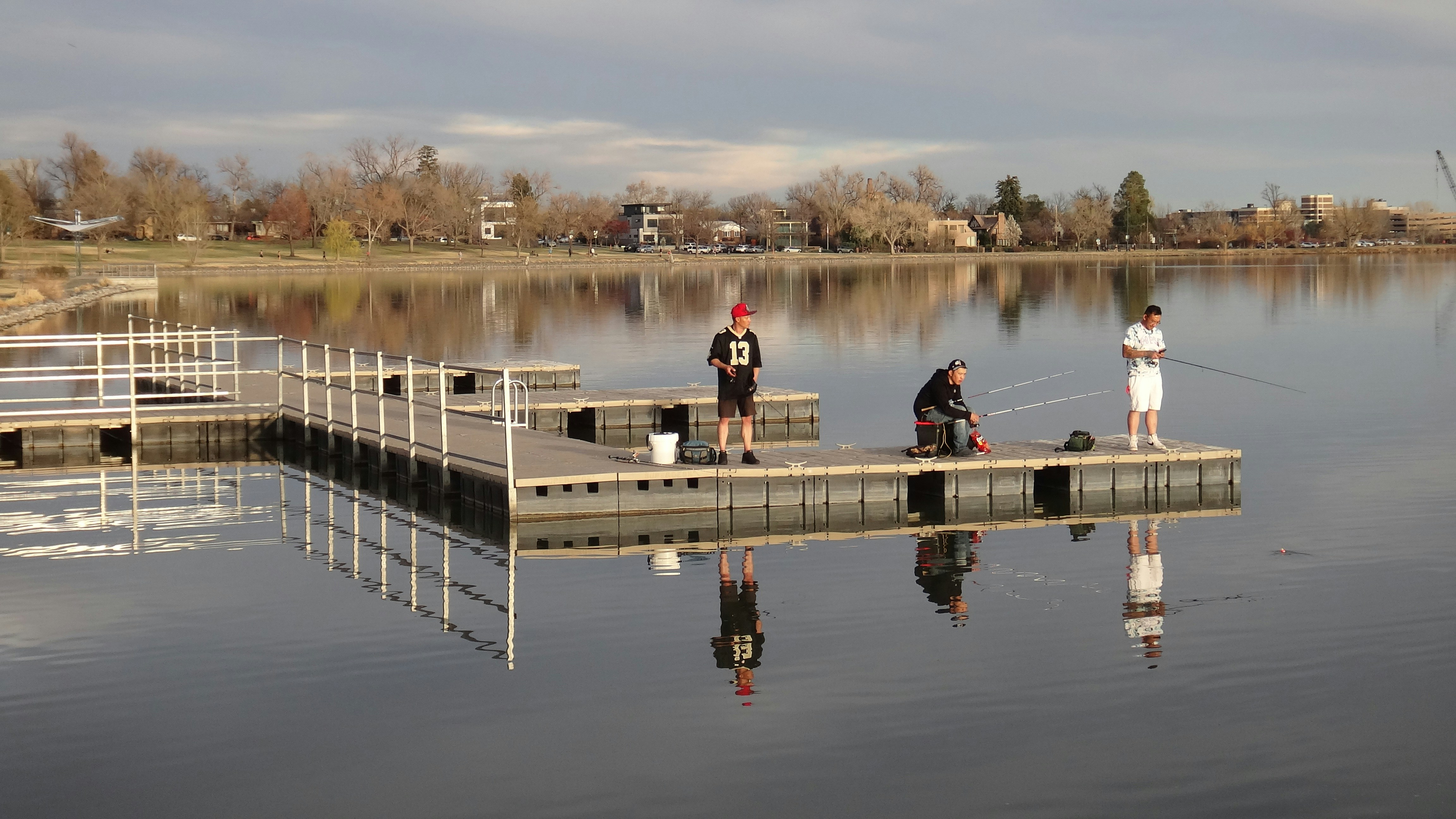 穏やかな湖の浮き桟橋から釣りをしている人々。