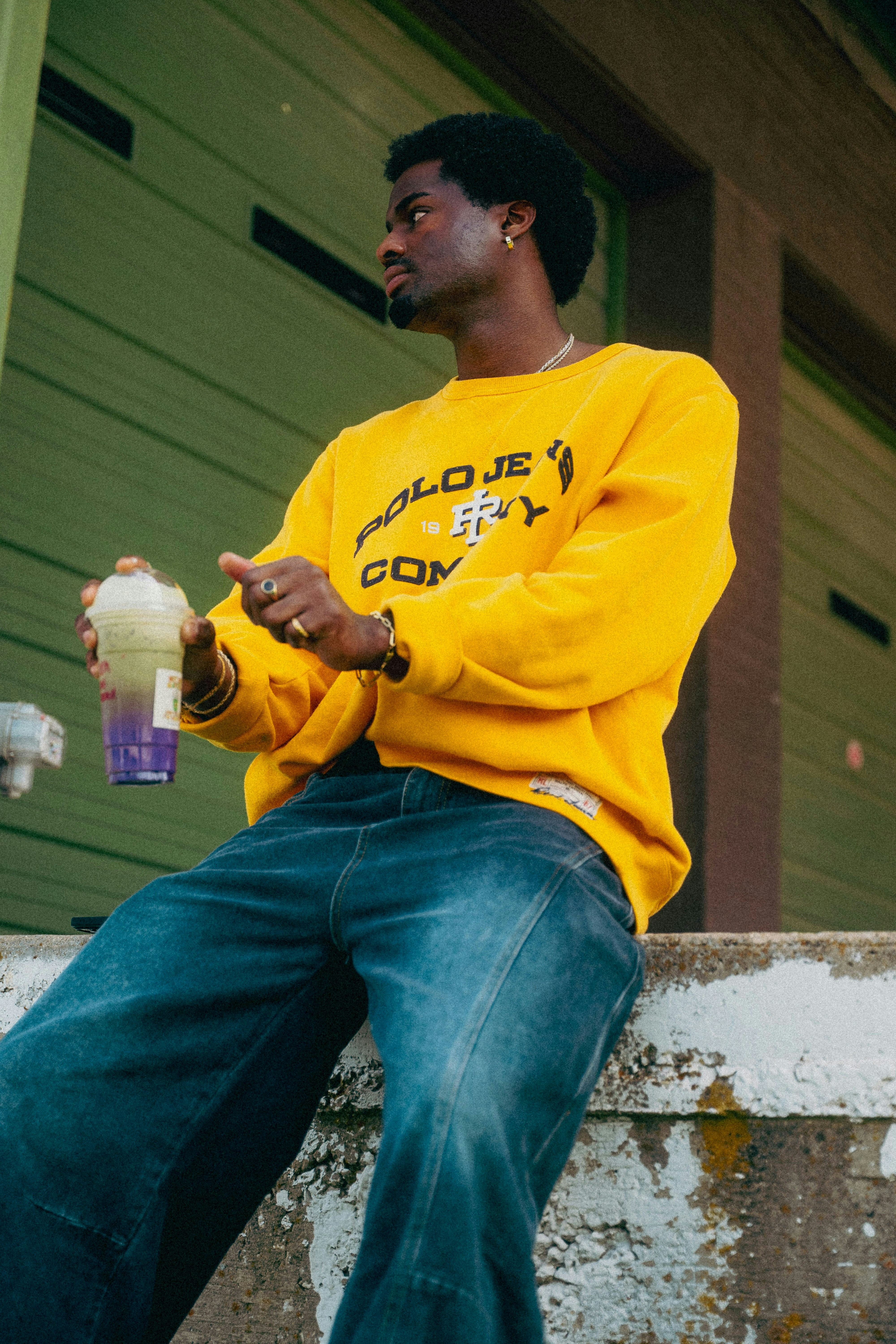 Man in yellow sweatshirt holding a drink