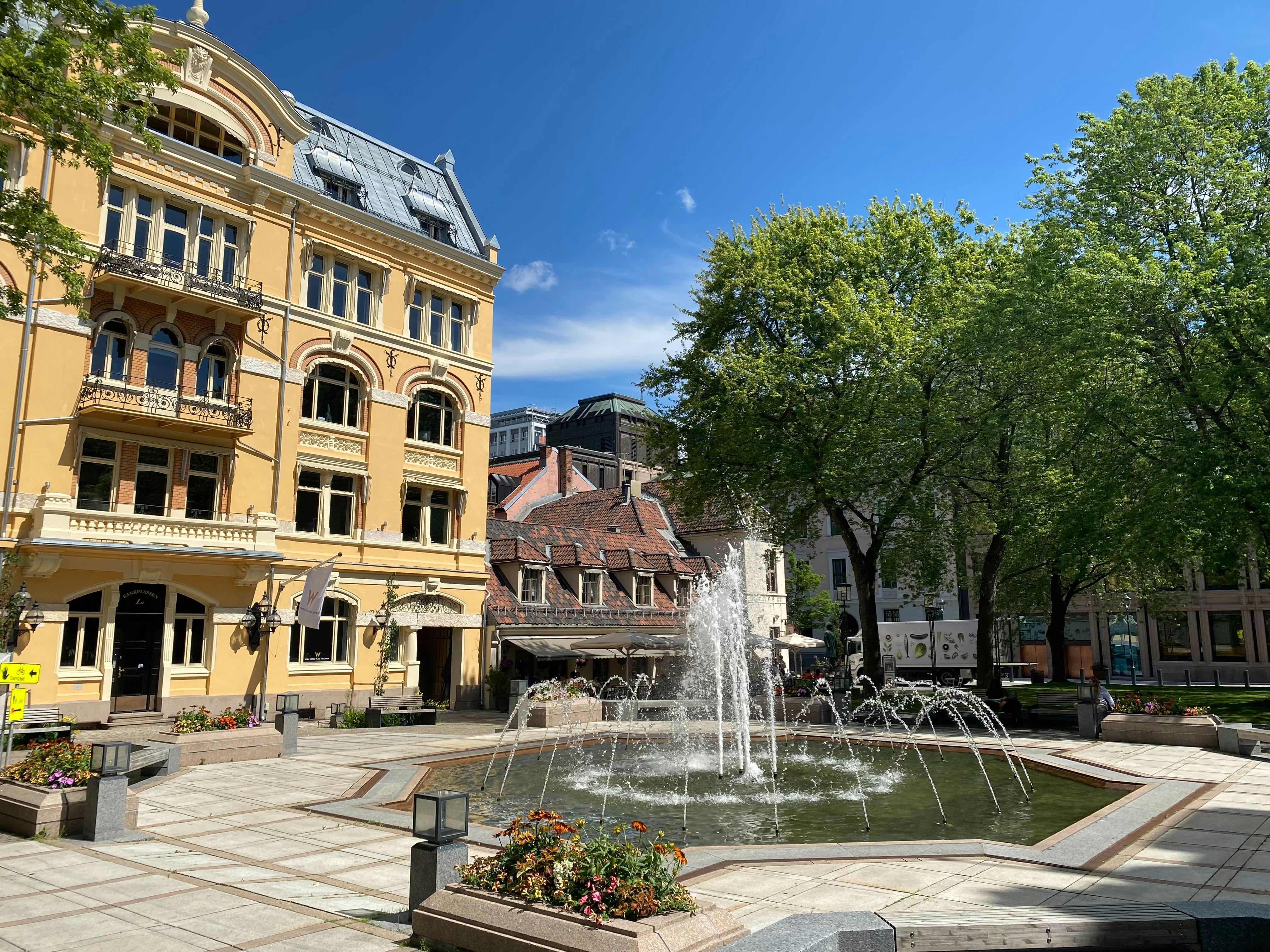 Ein gelbes Gebäude und ein Brunnen in einem Park.