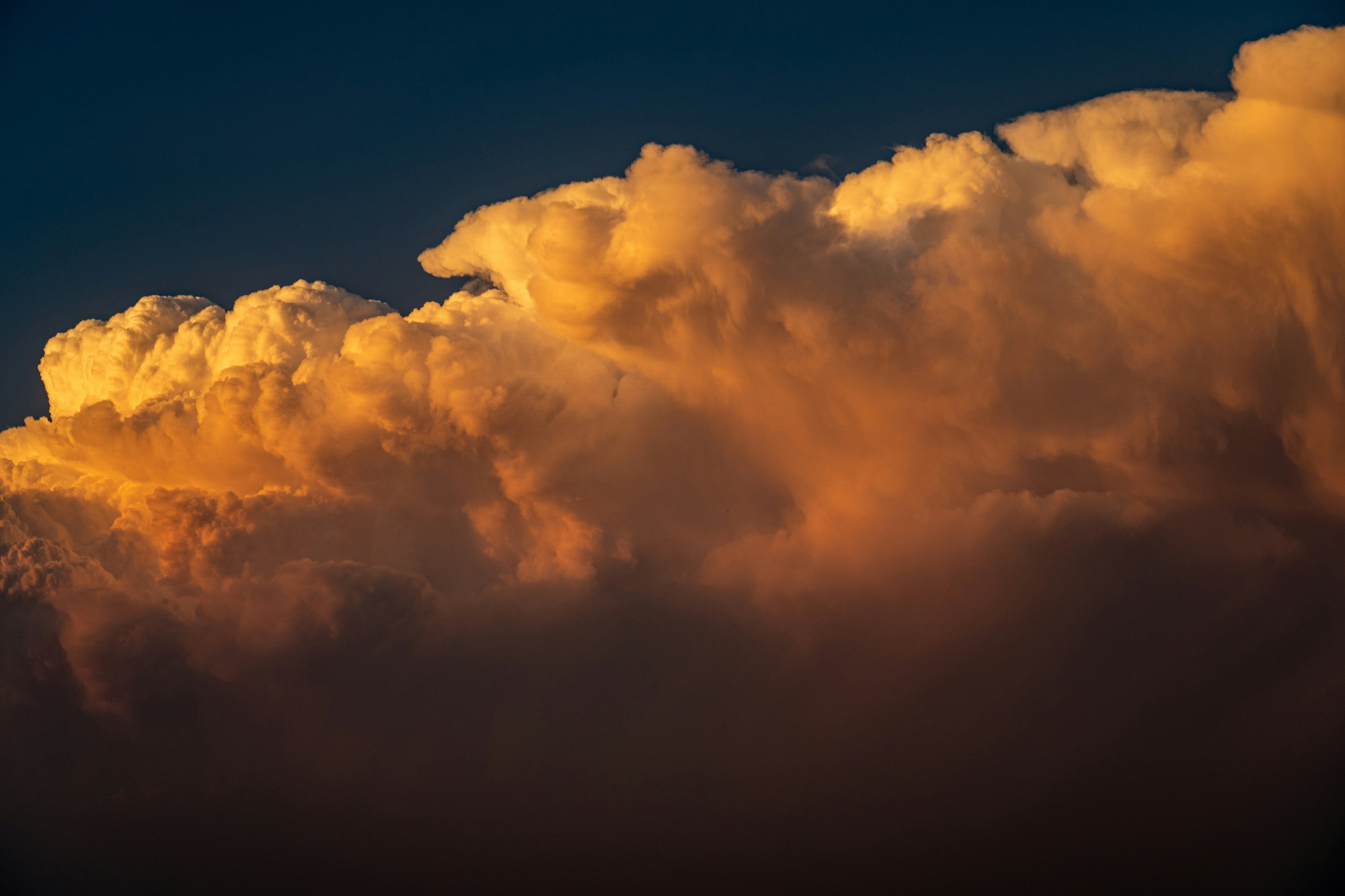 Nubes doradas iluminadas por el atardecer contra un cielo azul oscuro
