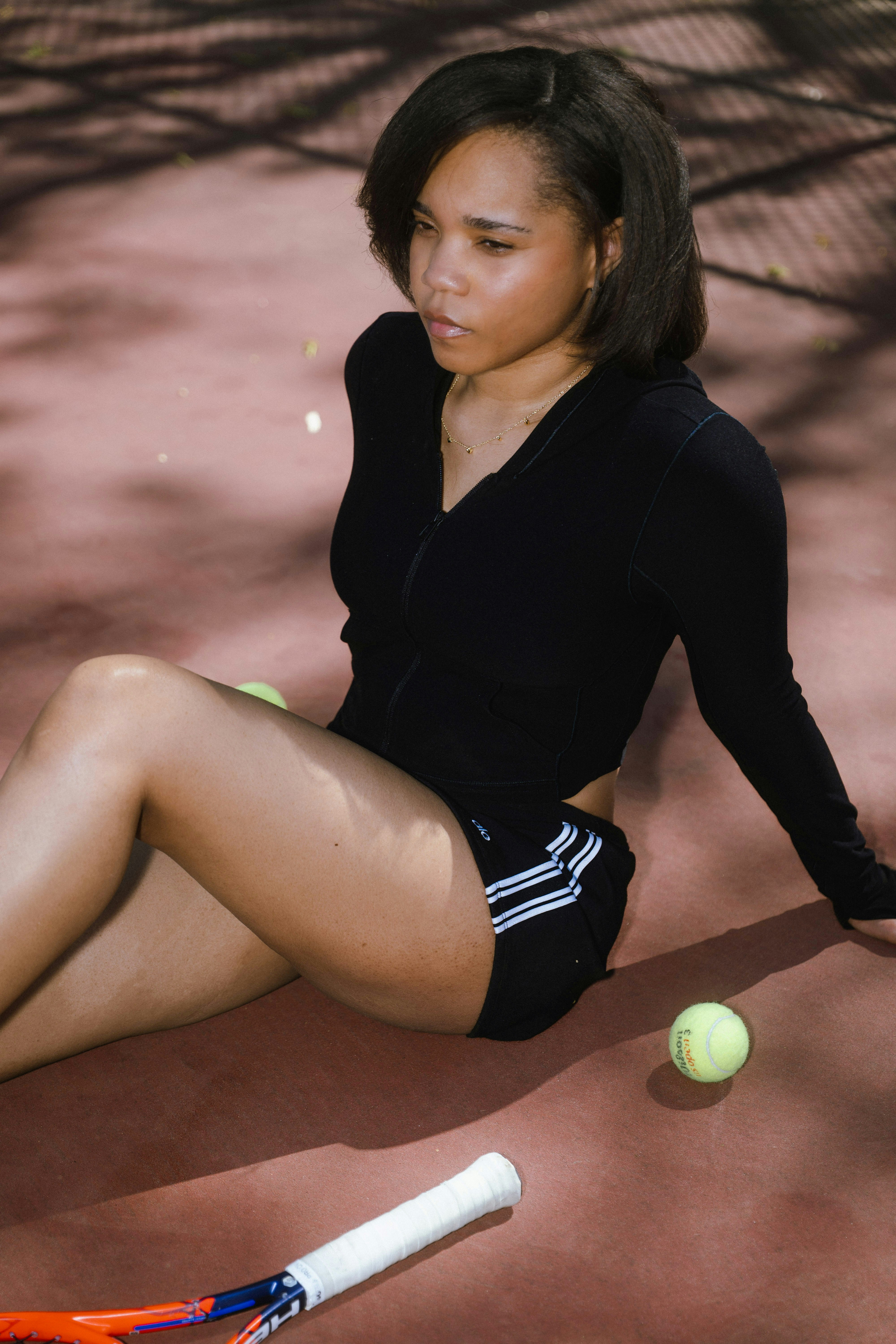 Young woman in athletic wear rests on tennis court.