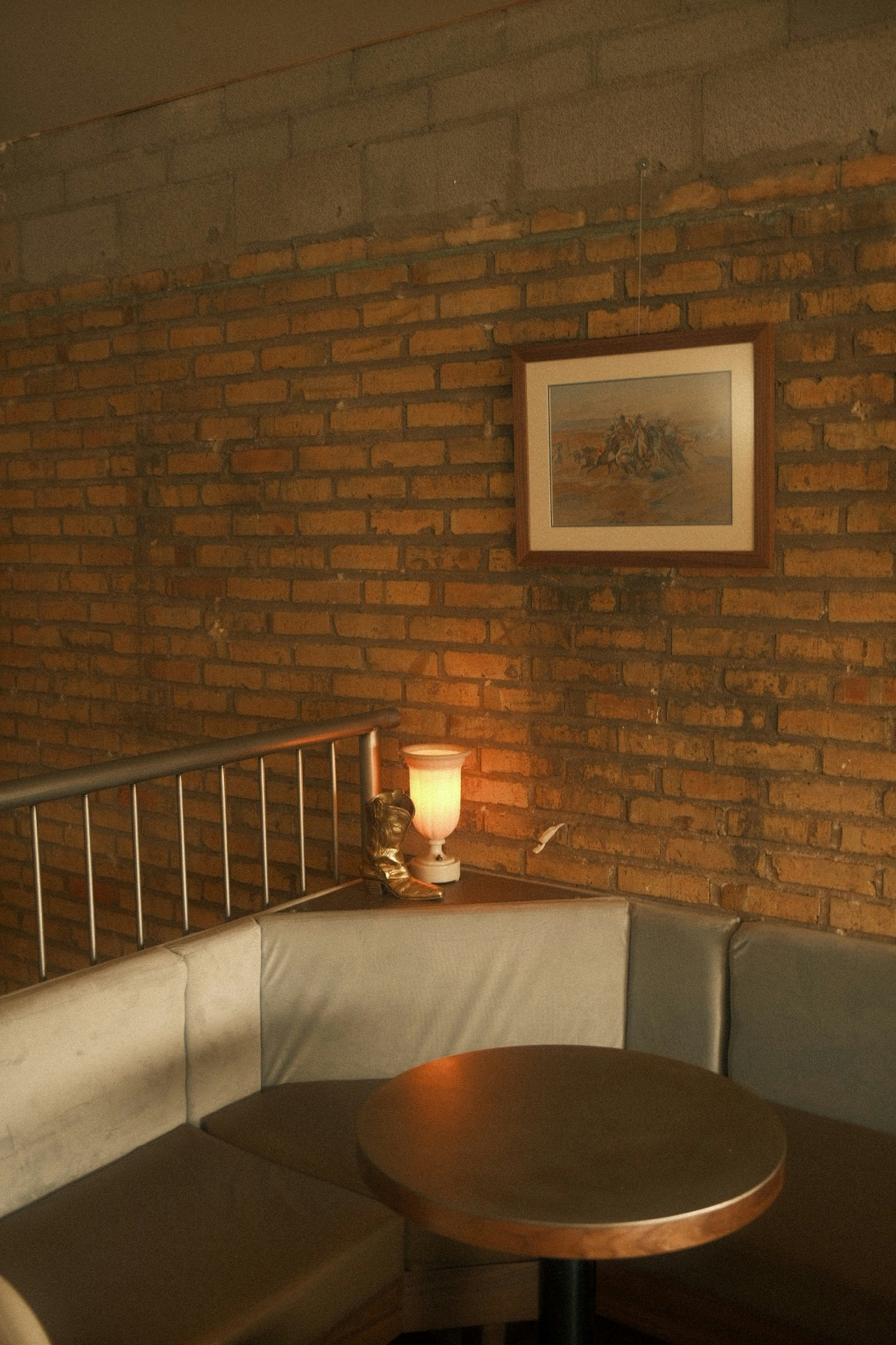 Corner booth with a round table and a lamp.