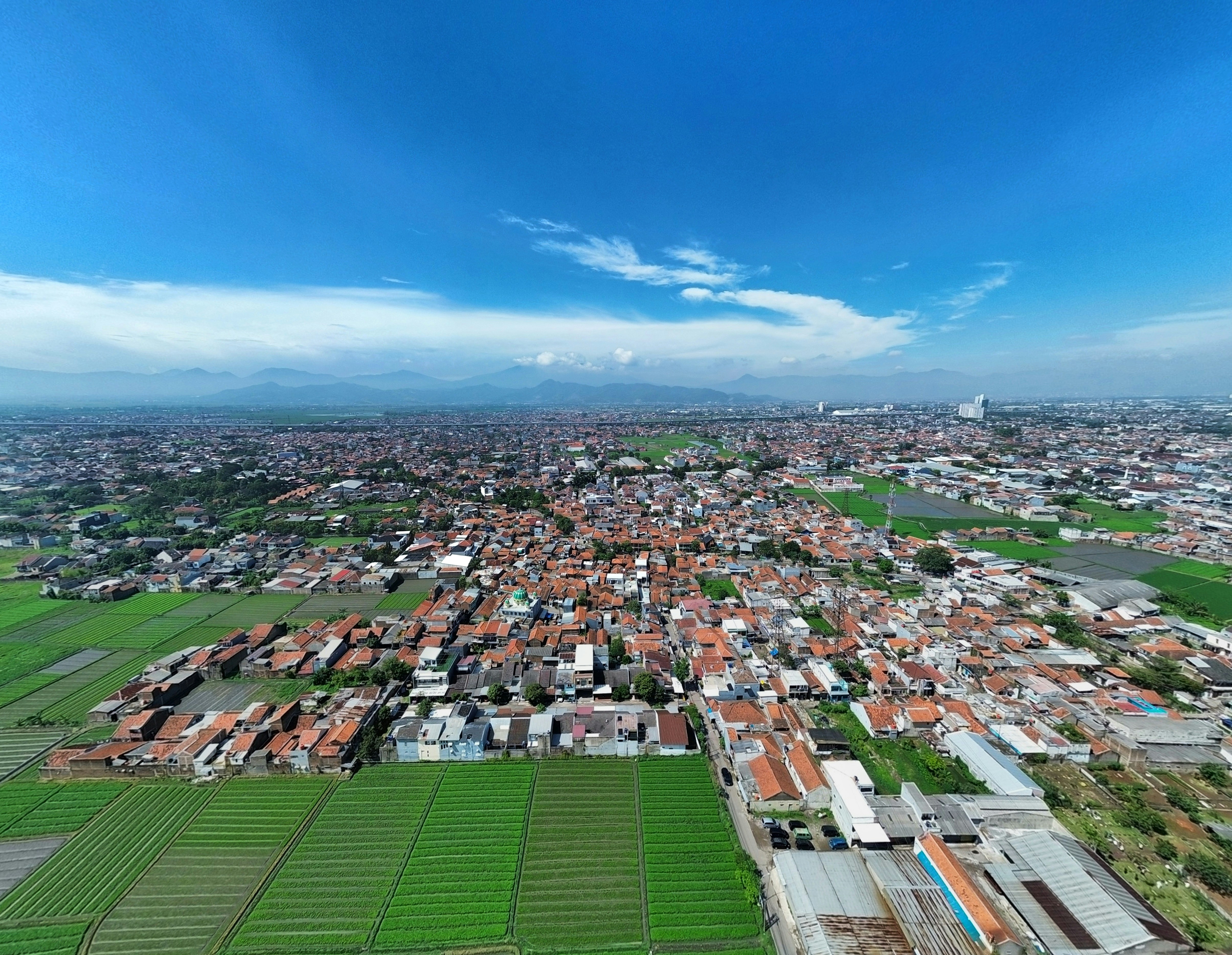 Vista aérea de uma cidade extensa com campos verdes.