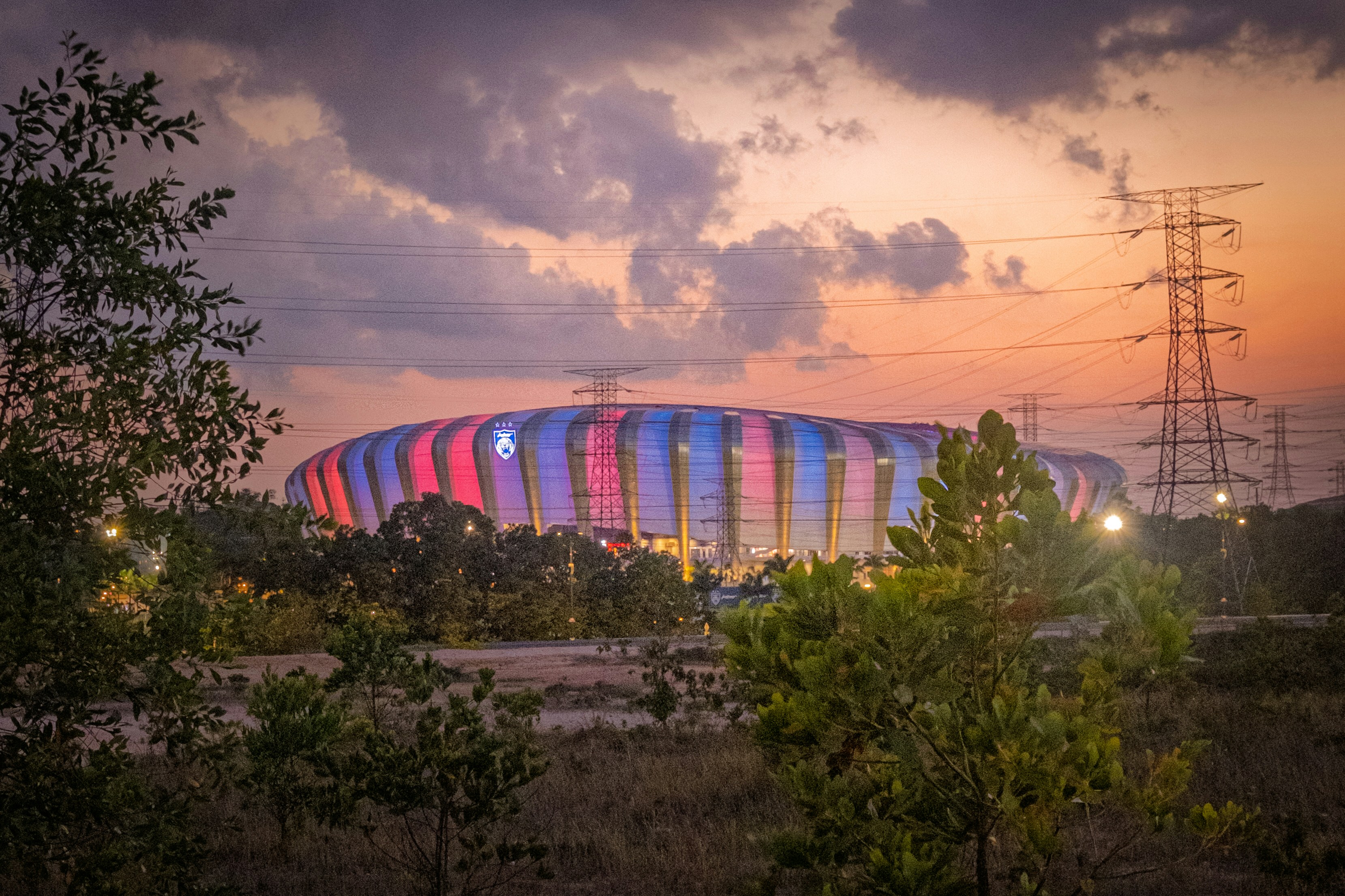 Illuminated stadium glows under a dramatic sunset sky.