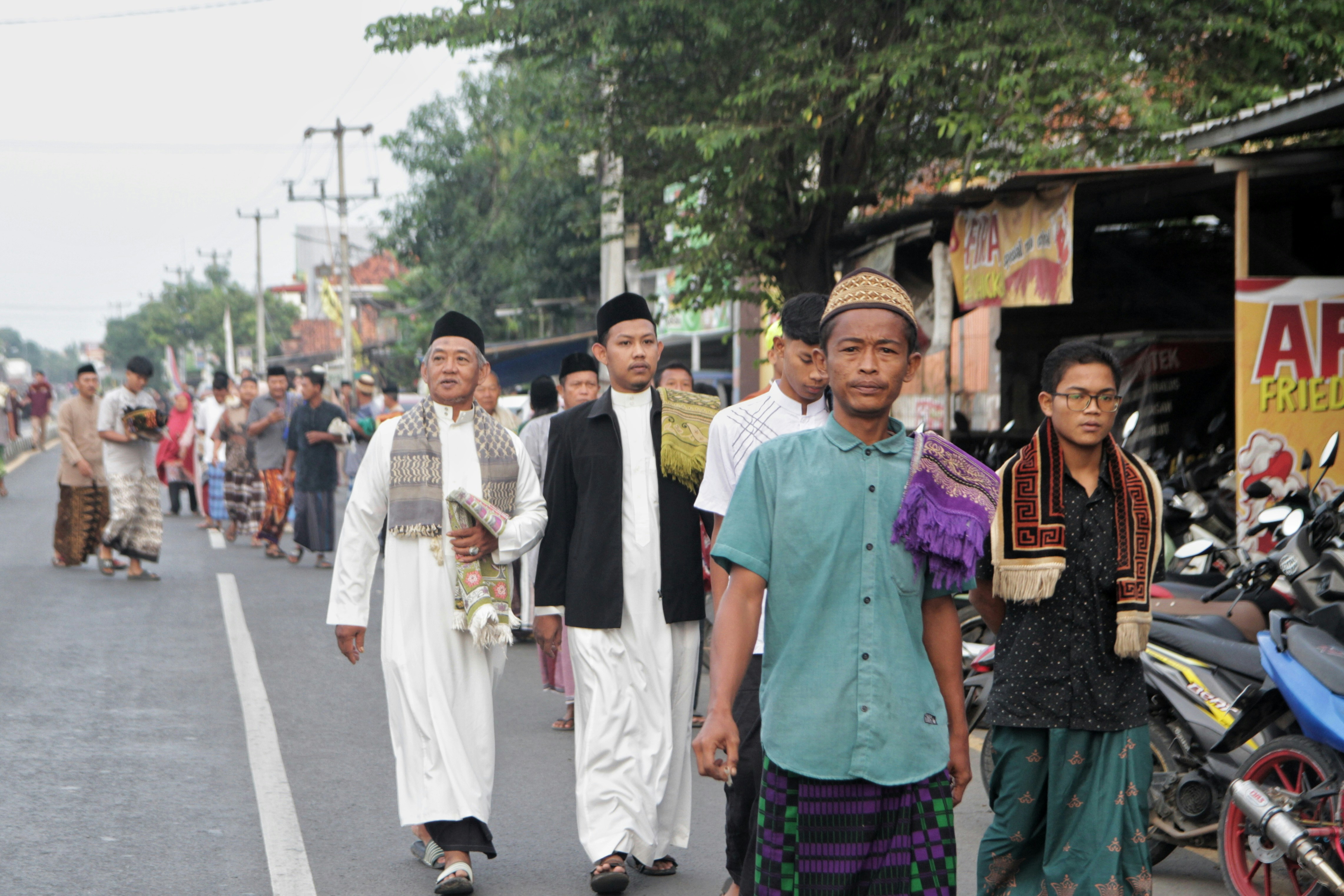 Pria berpakaian tradisional Islam berjalan di jalan.