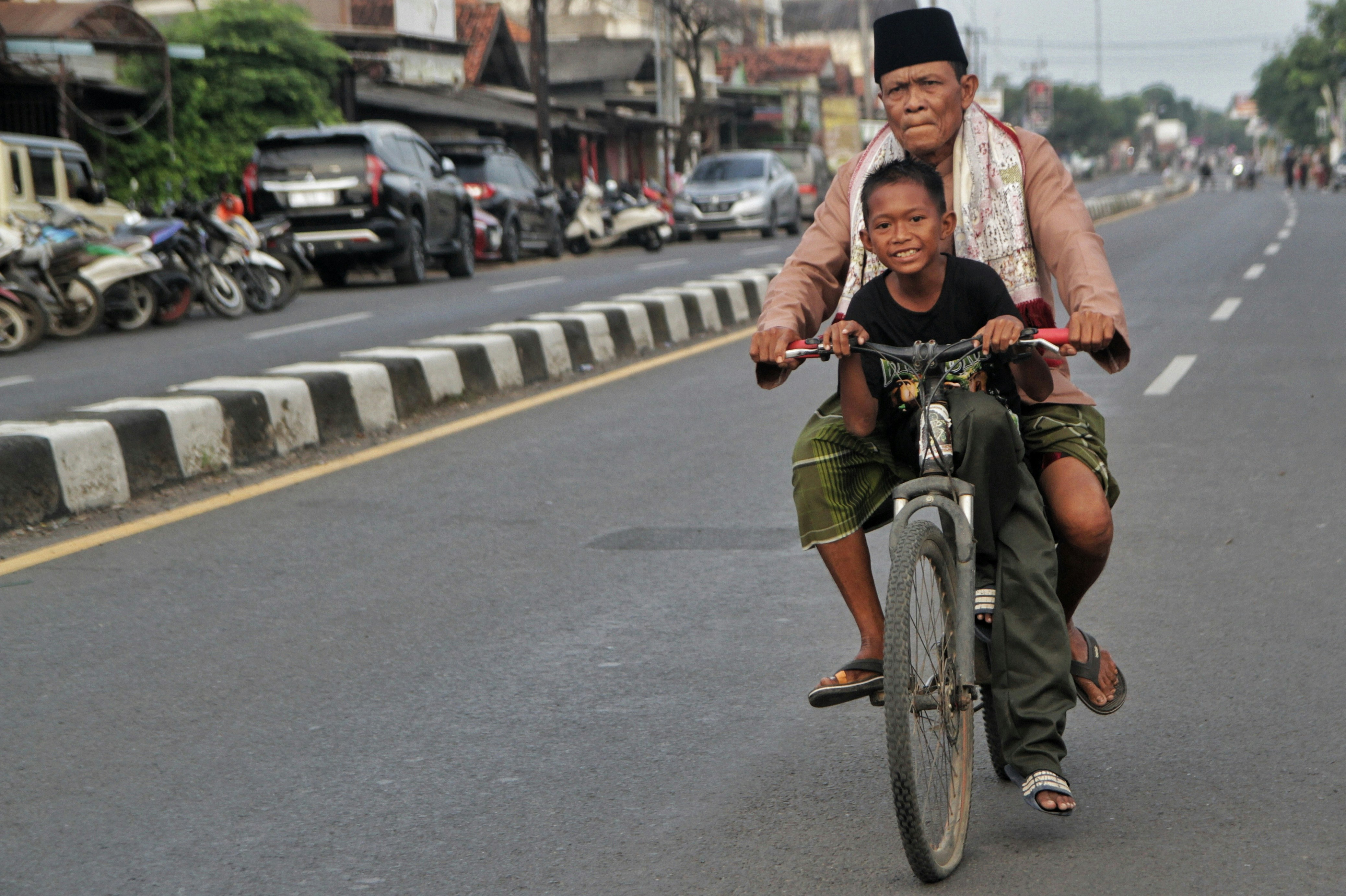 man and boy ride a bicycle on a street