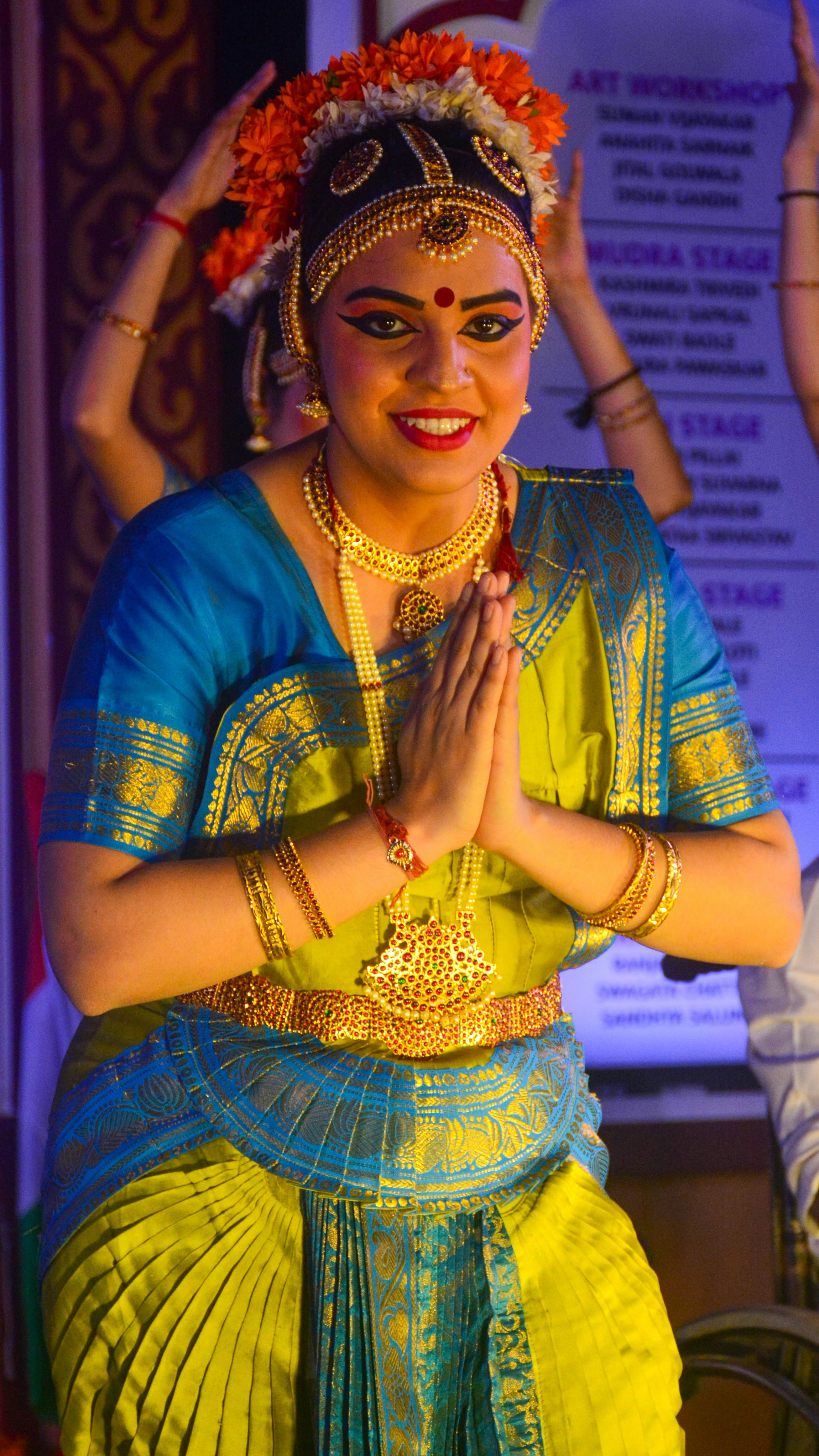 Une femme en costume de danse indienne traditionnelle, les mains jointes.