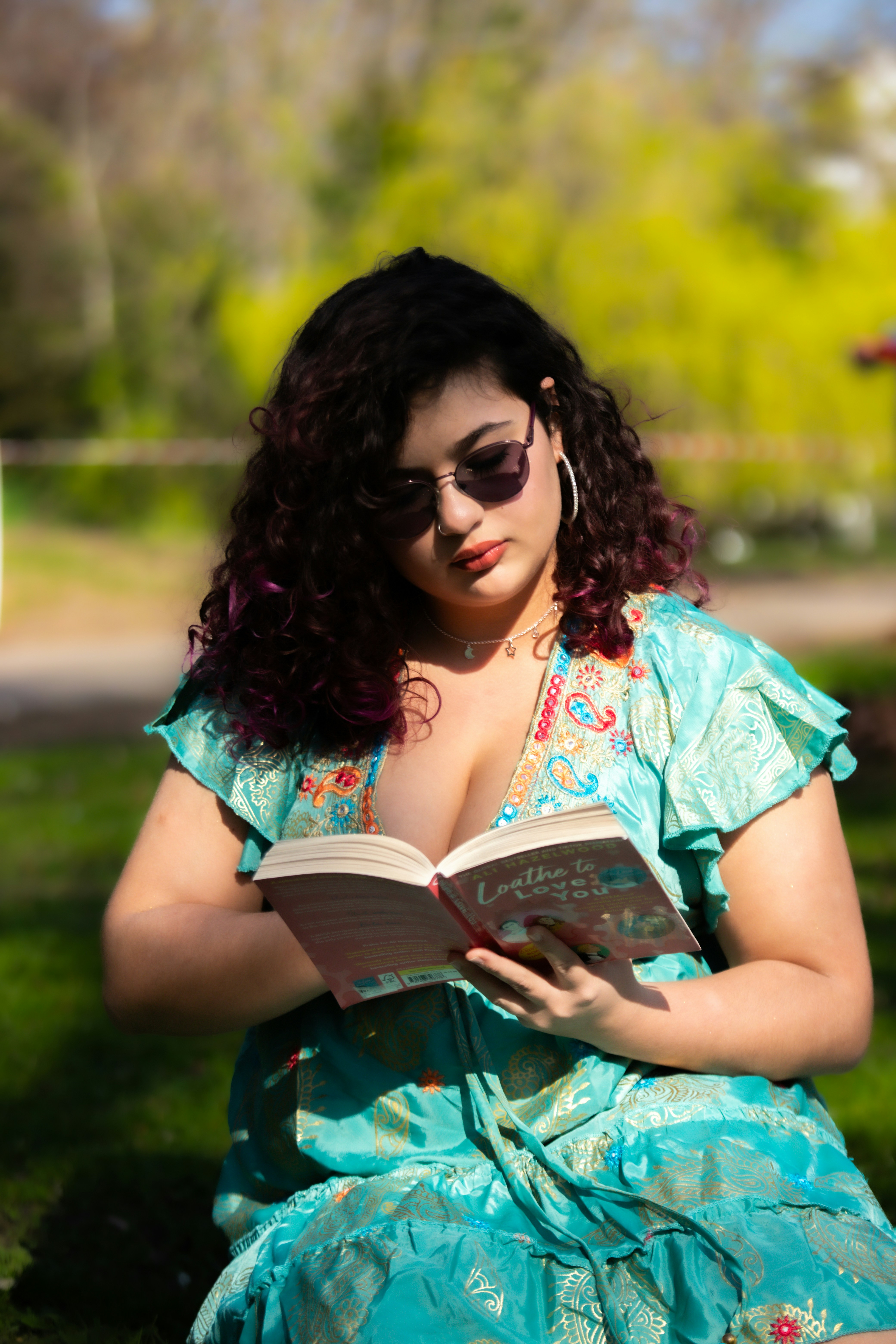 Una donna che legge un libro all'aperto in una giornata di sole.