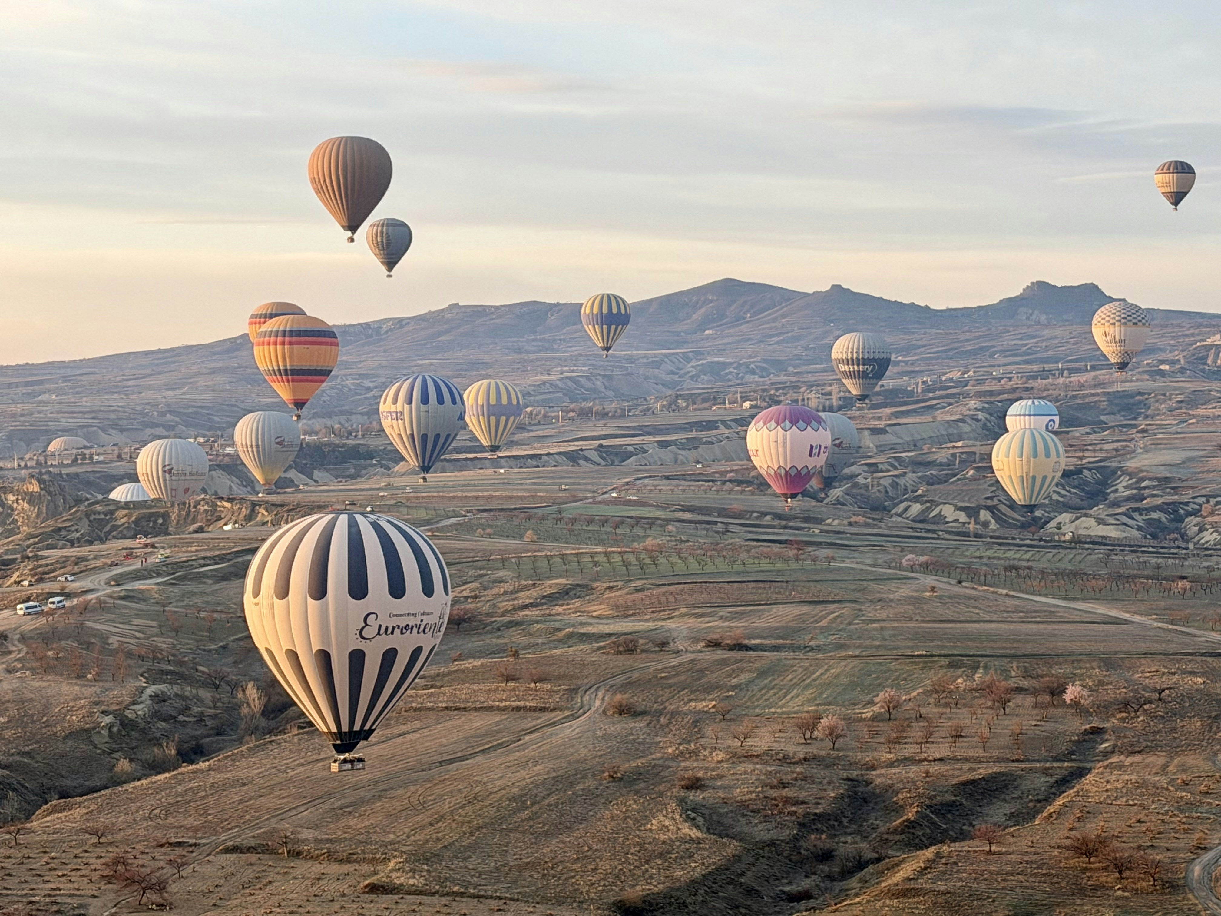 Hot air balloons rising over Cappadocia's rocky valleys at sunrise