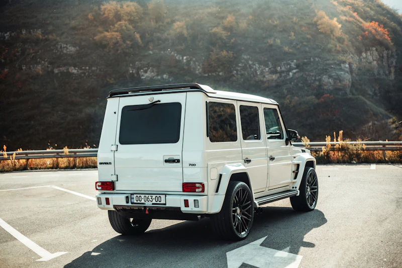 A white luxury SUV parked on asphalt with majestic mountains behind