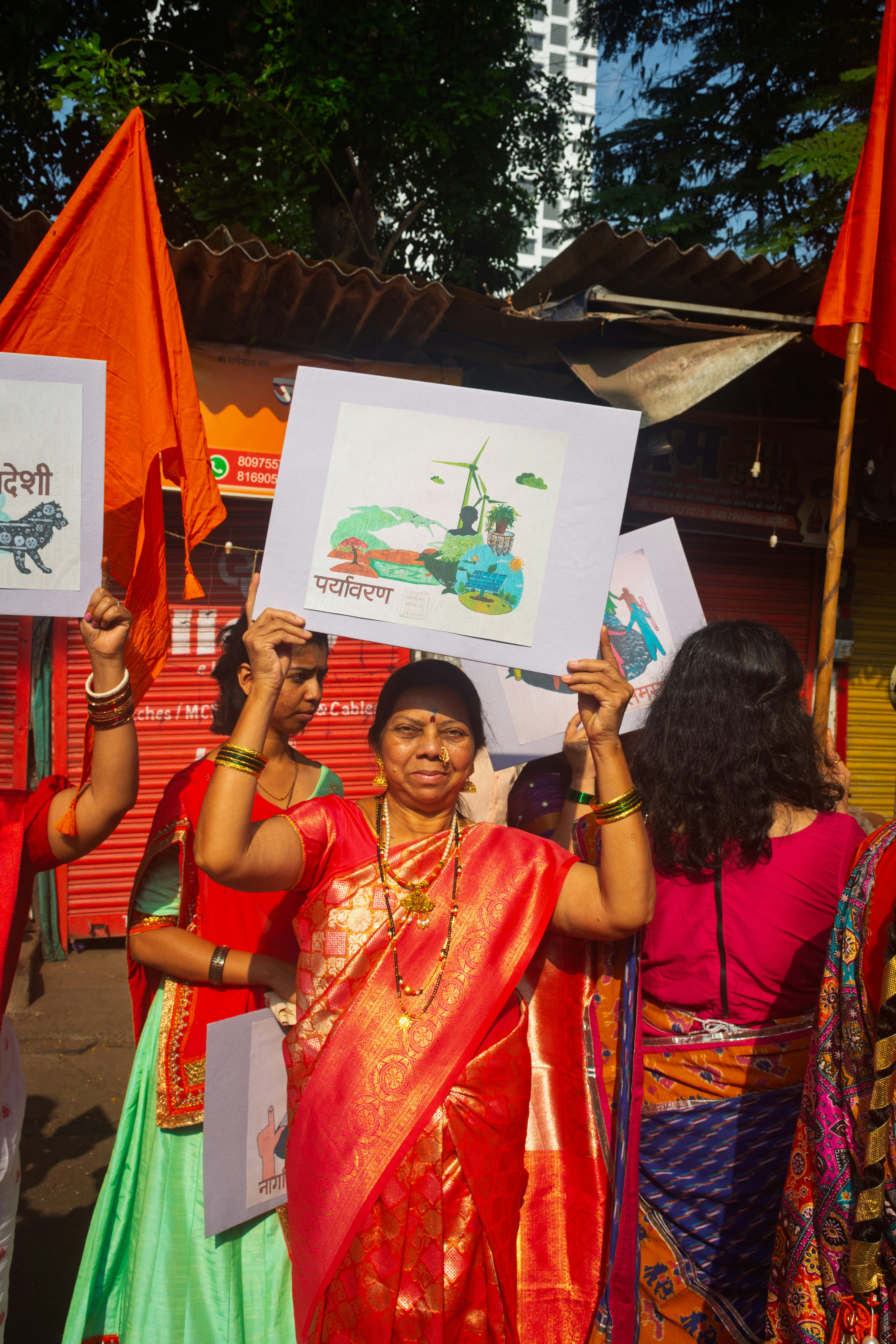Wanita dengan pakaian tradisional India memegang spanduk di rapat umum.