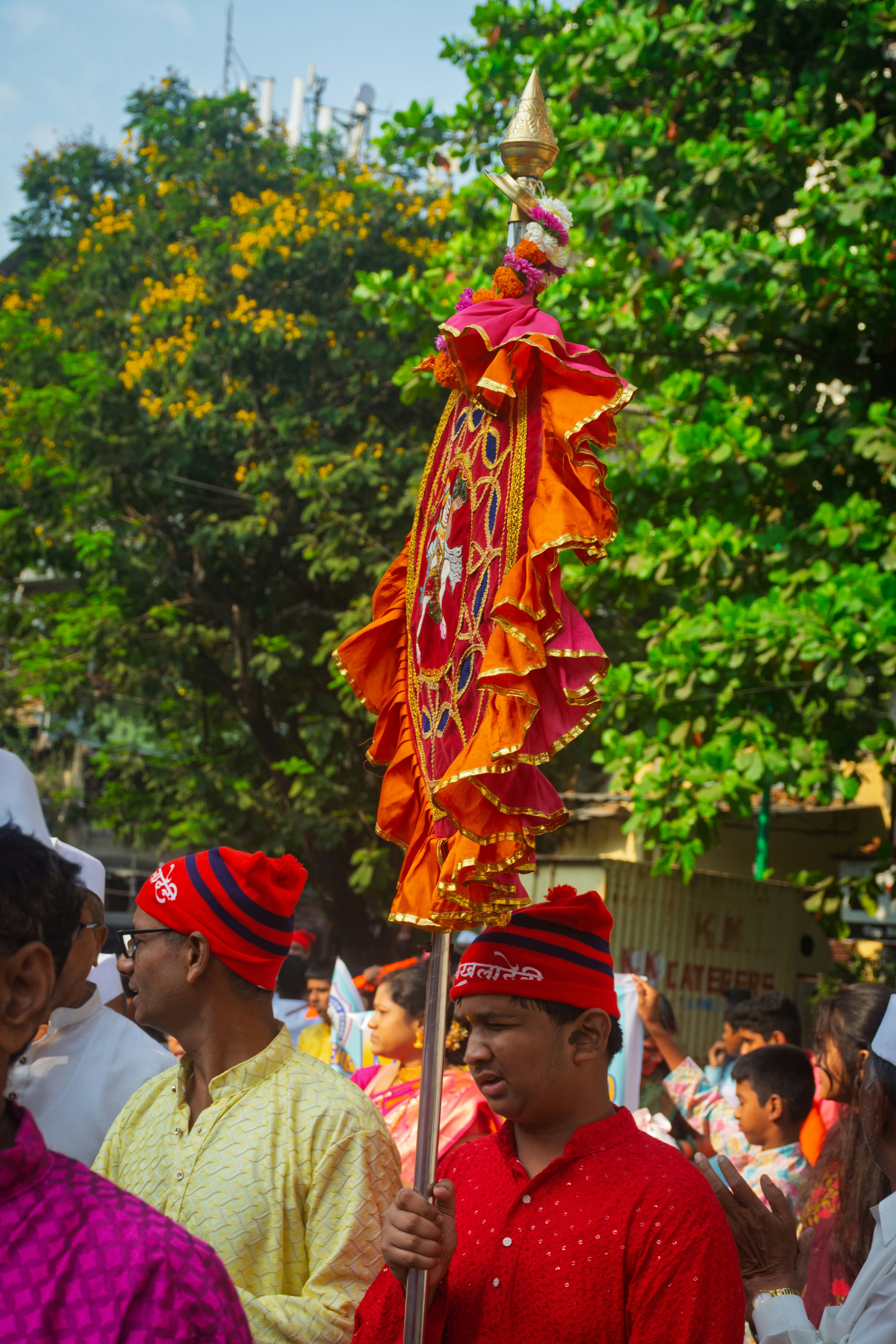 People in red hats holding a decorative flag