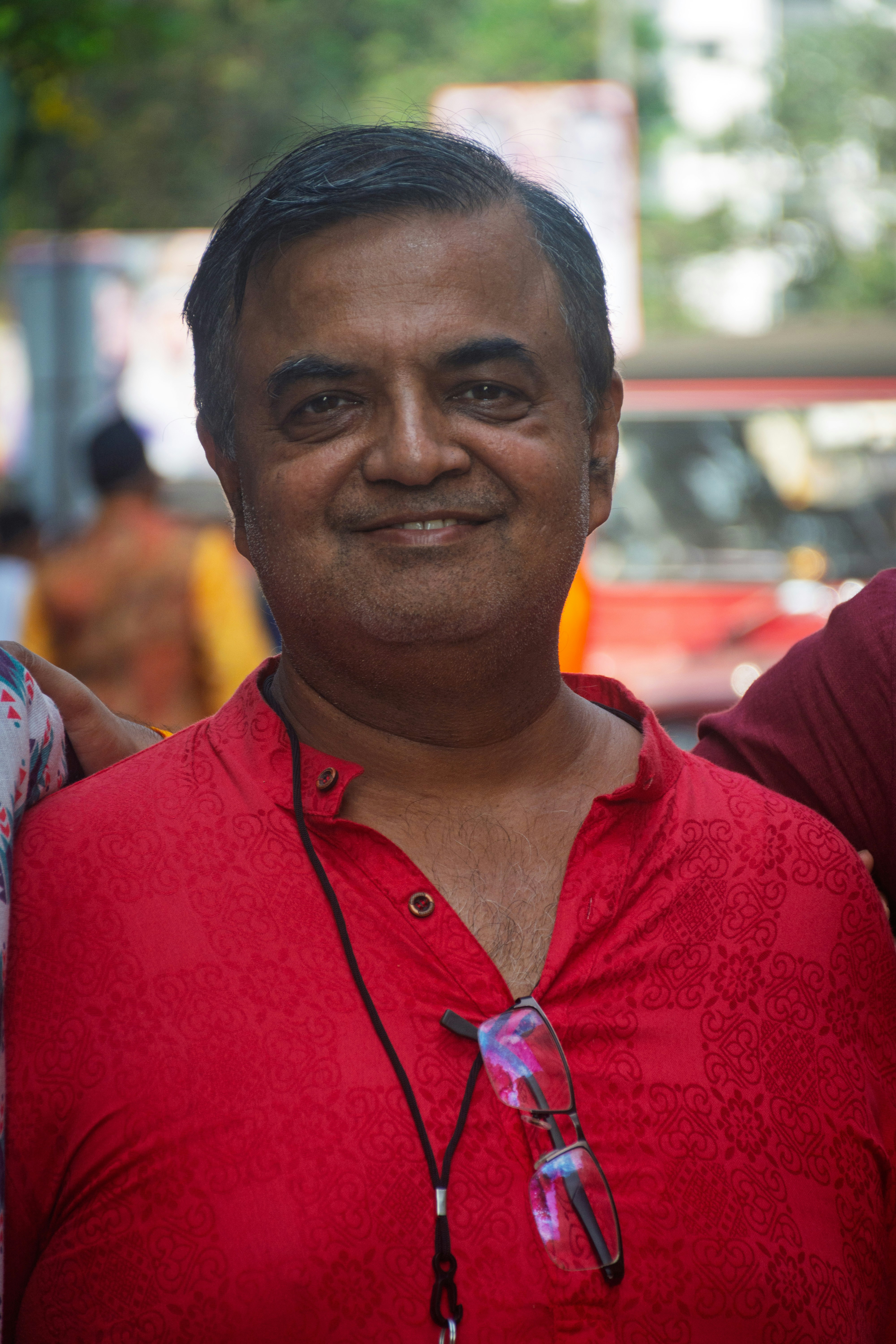 A smiling man in a red shirt with glasses