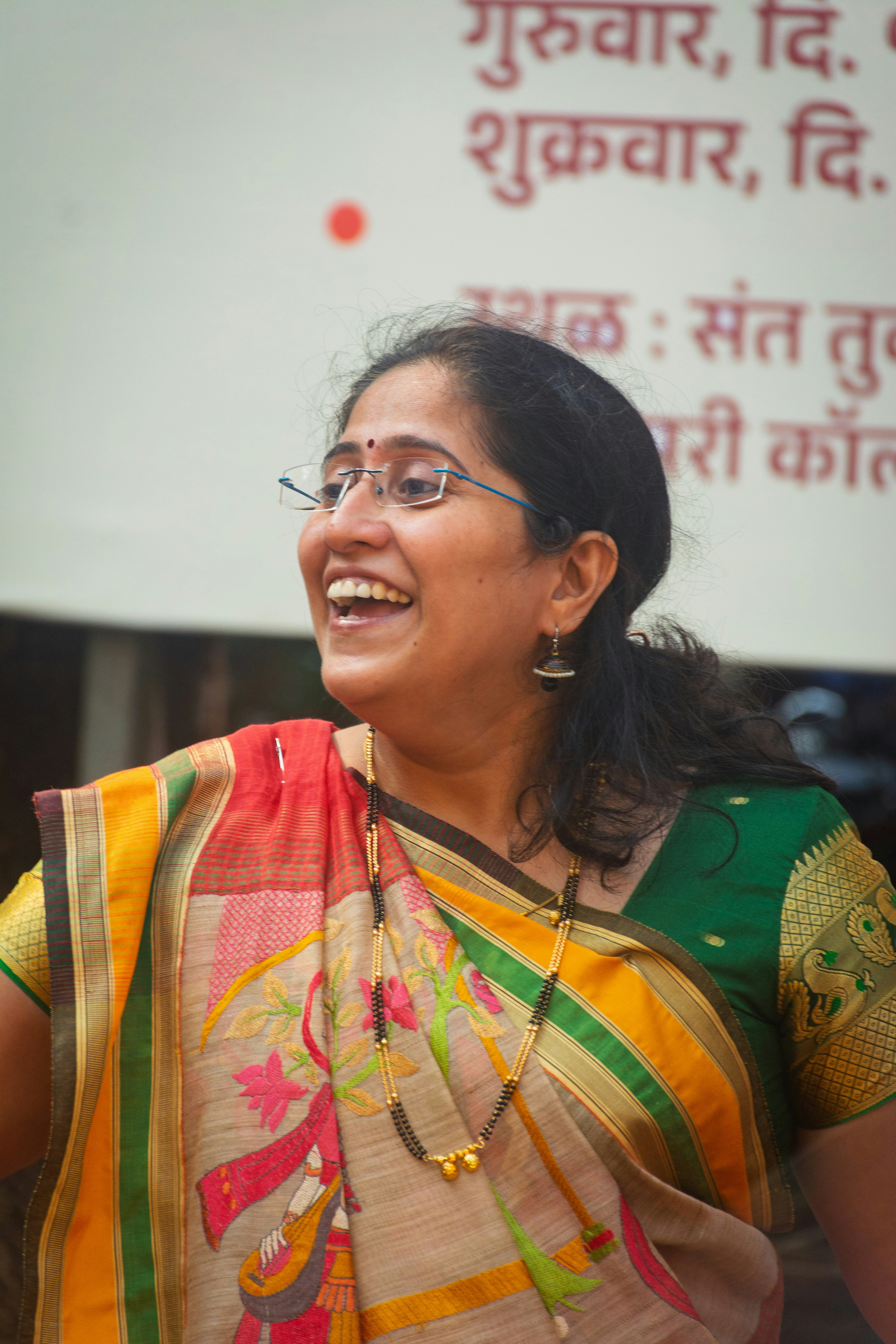A woman in a colorful sari laughs heartily