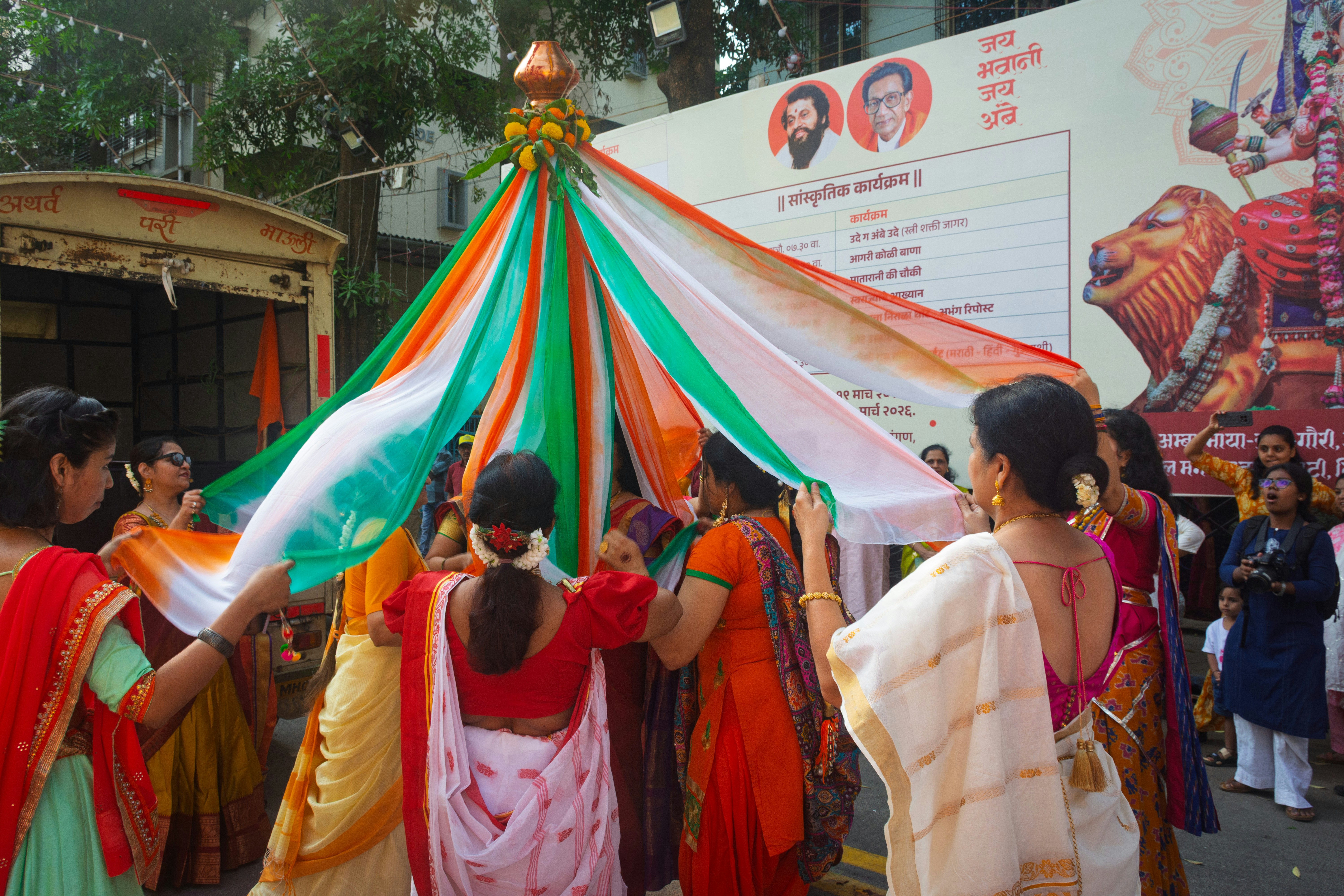 Women in colorful saris celebrating under draped fabric.