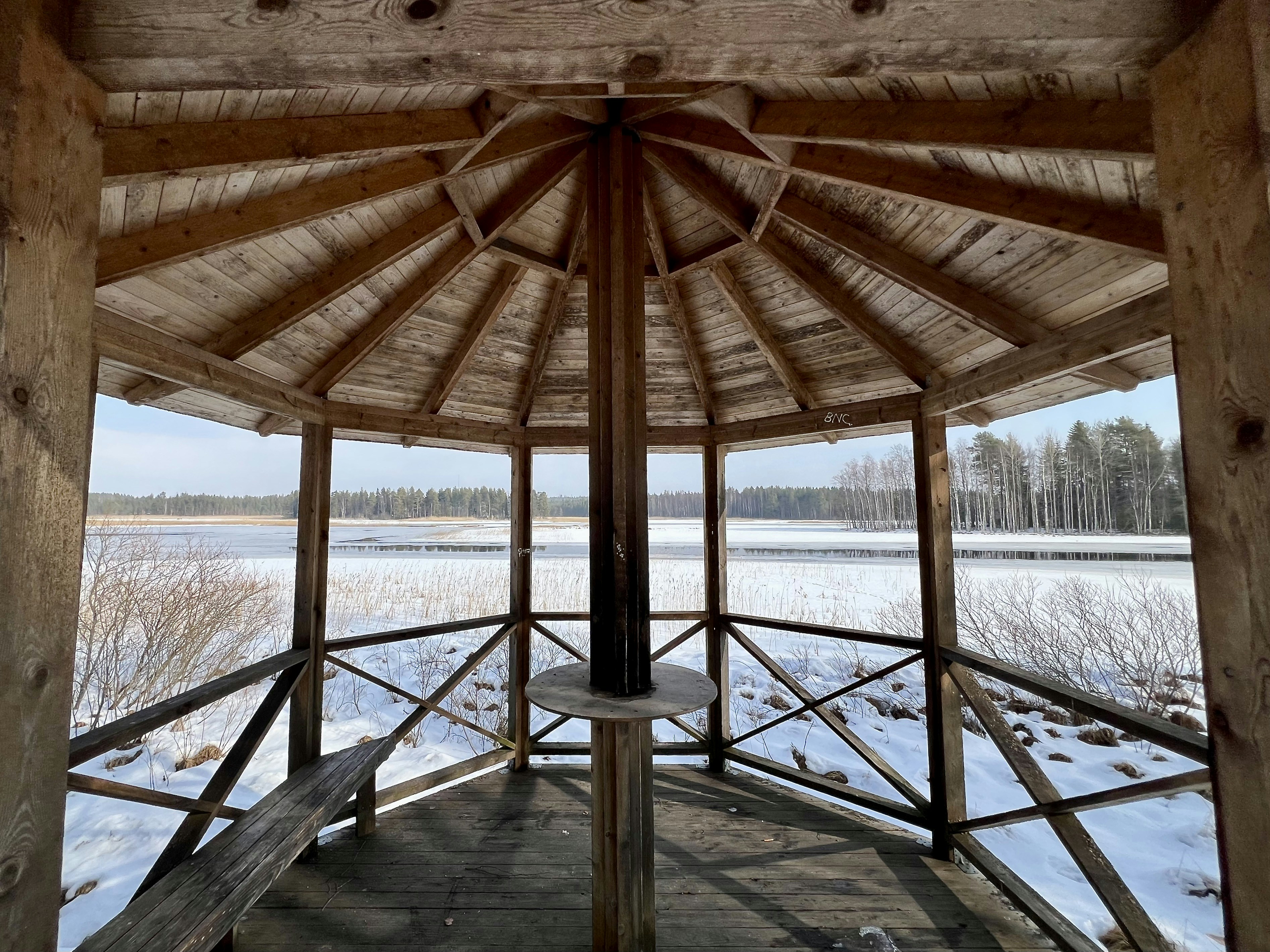 Wooden gazebo overlooking a frozen lake in winter