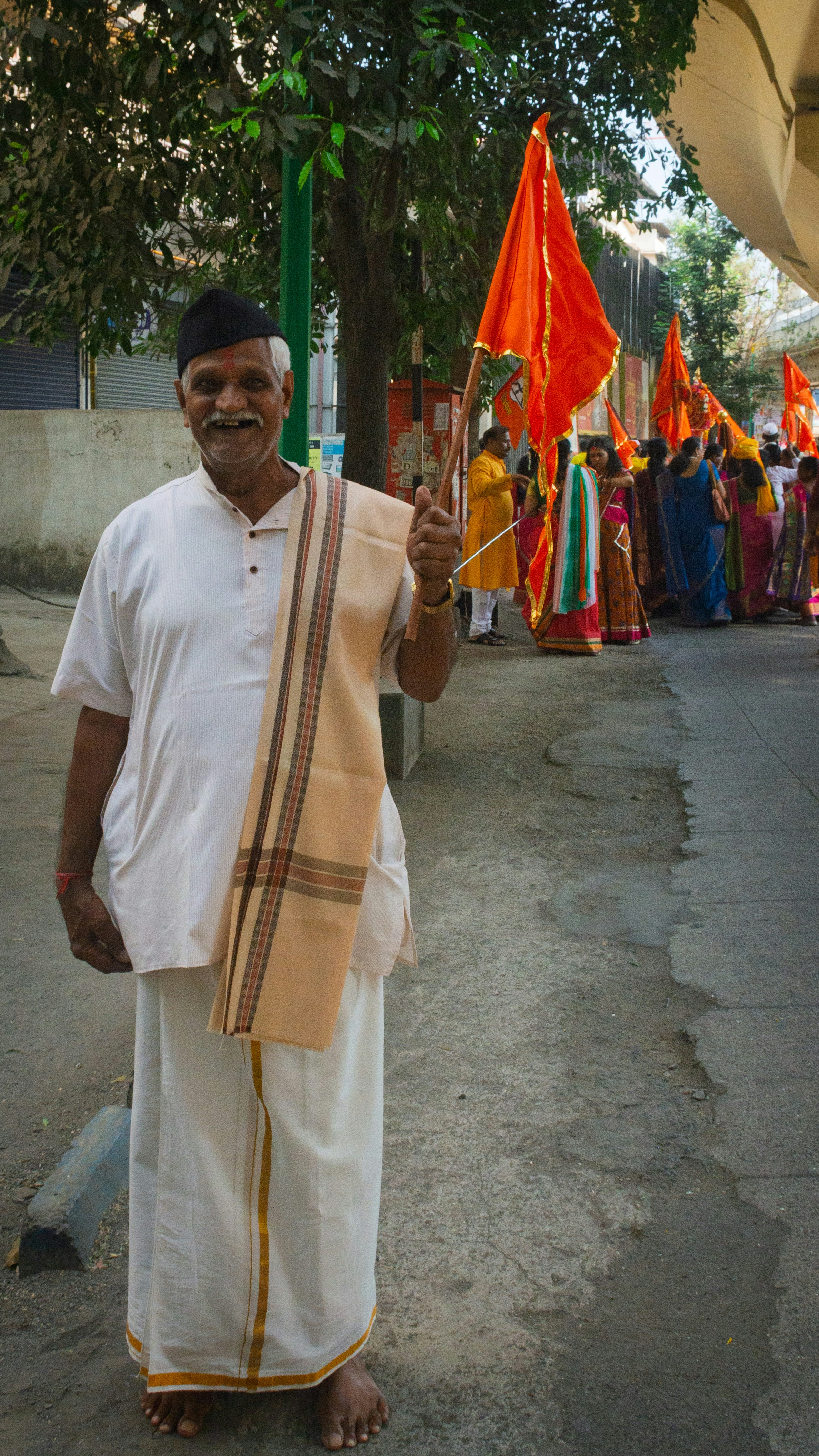 Elderly man in traditional indian attire holds orange flag