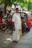 An elderly indian man in traditional clothing stands outdoors.