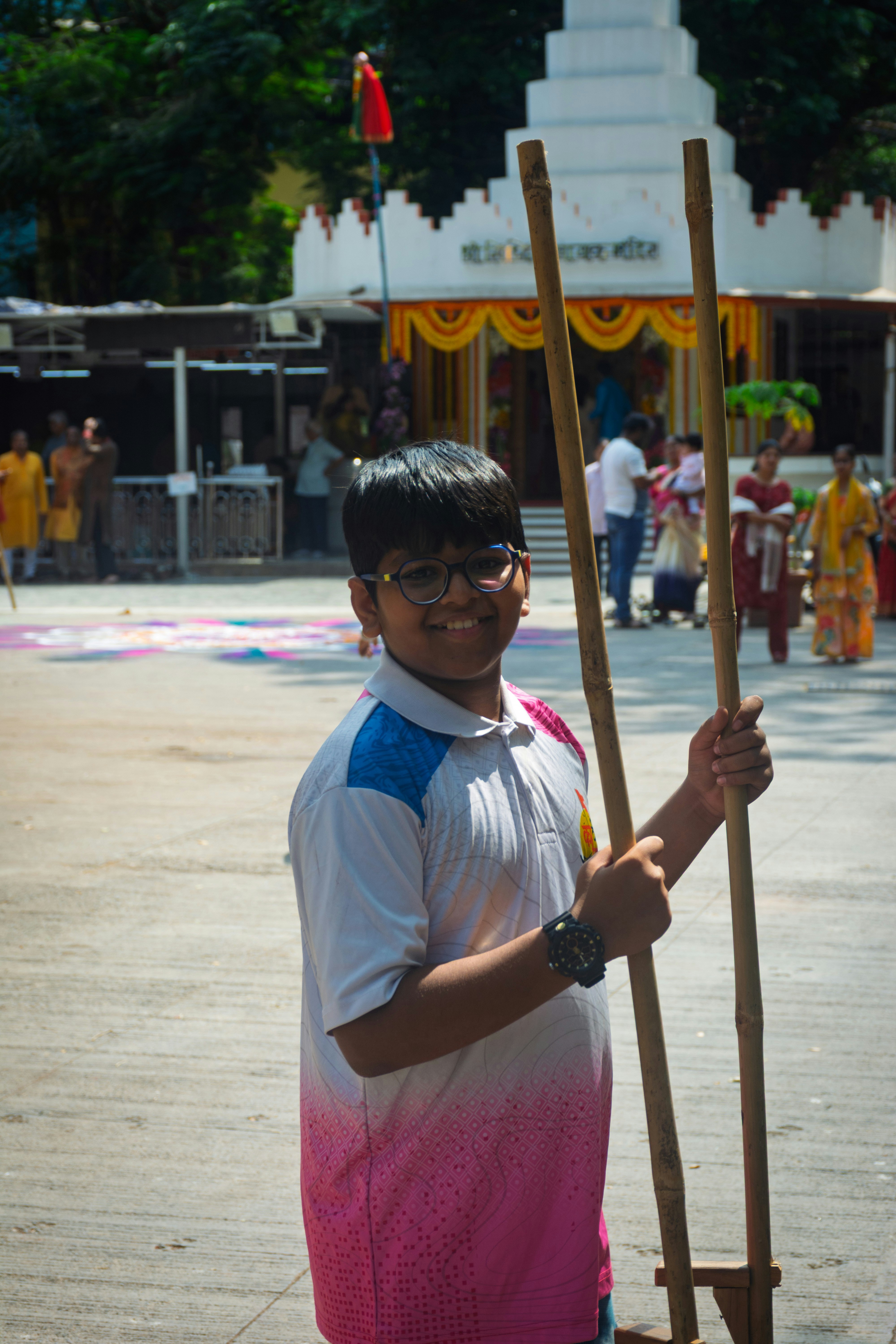 A boy smiles holding stilts at an outdoor event