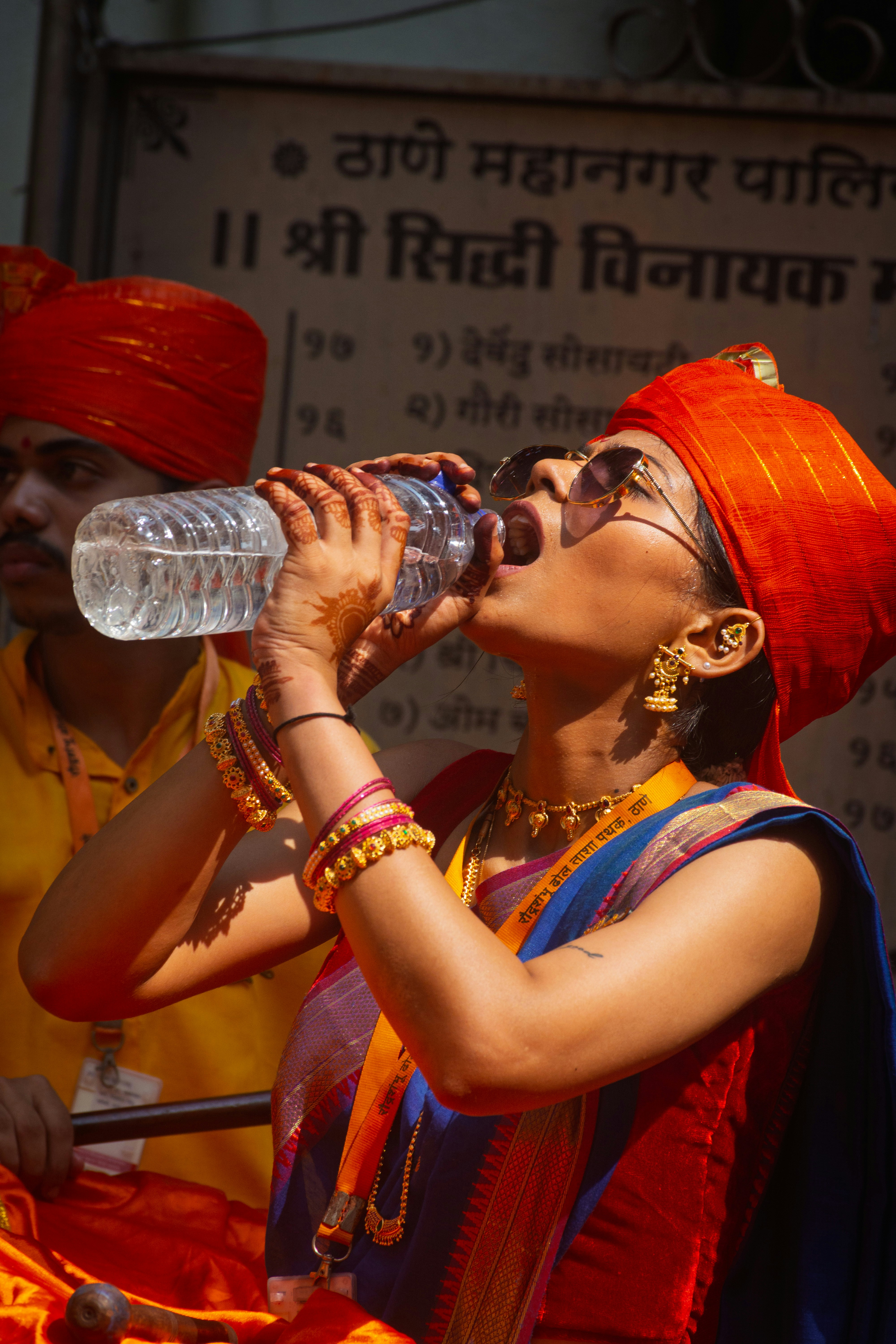 Woman in traditional attire drinks water from bottle