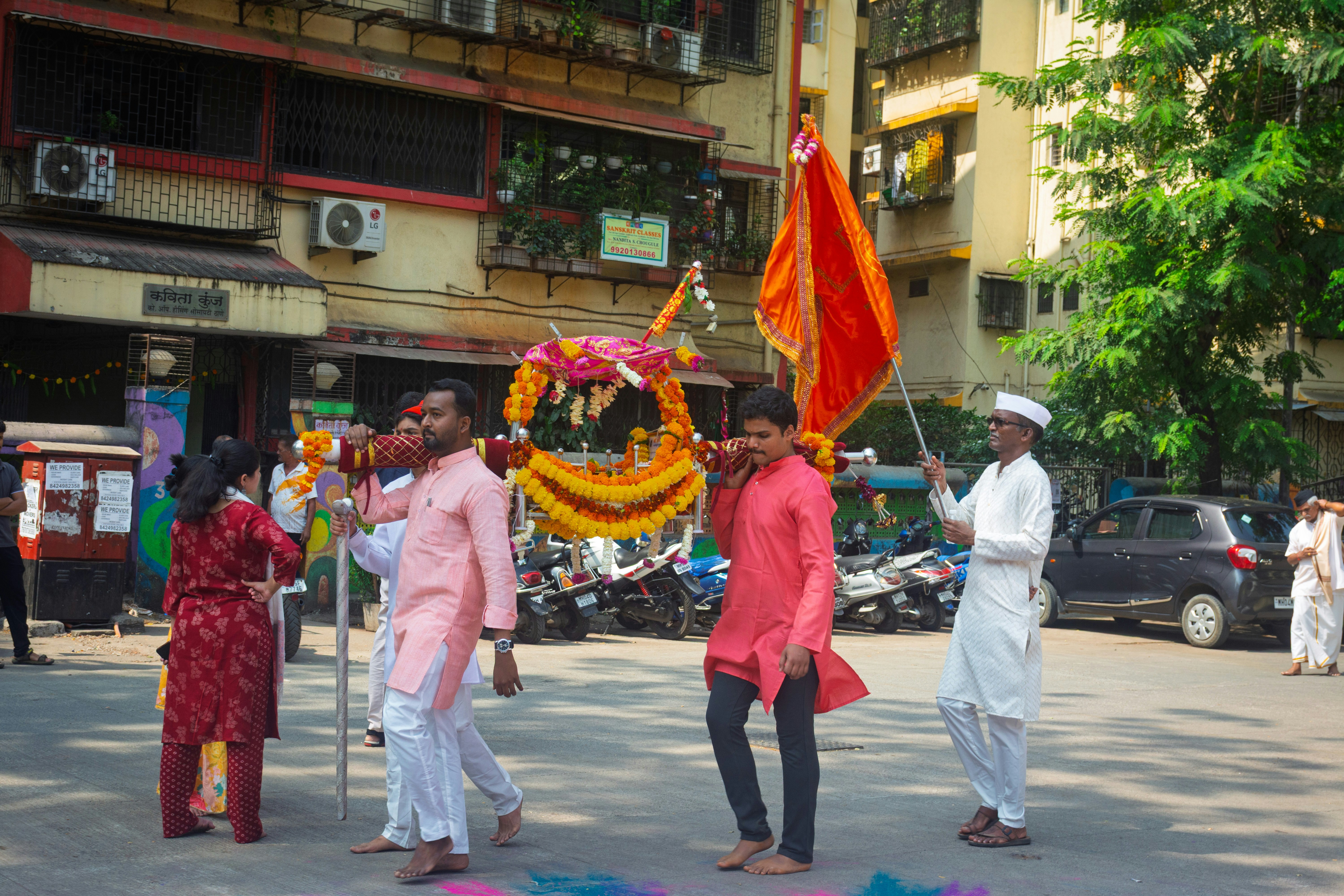 People carry a decorated palanquin with a flag.