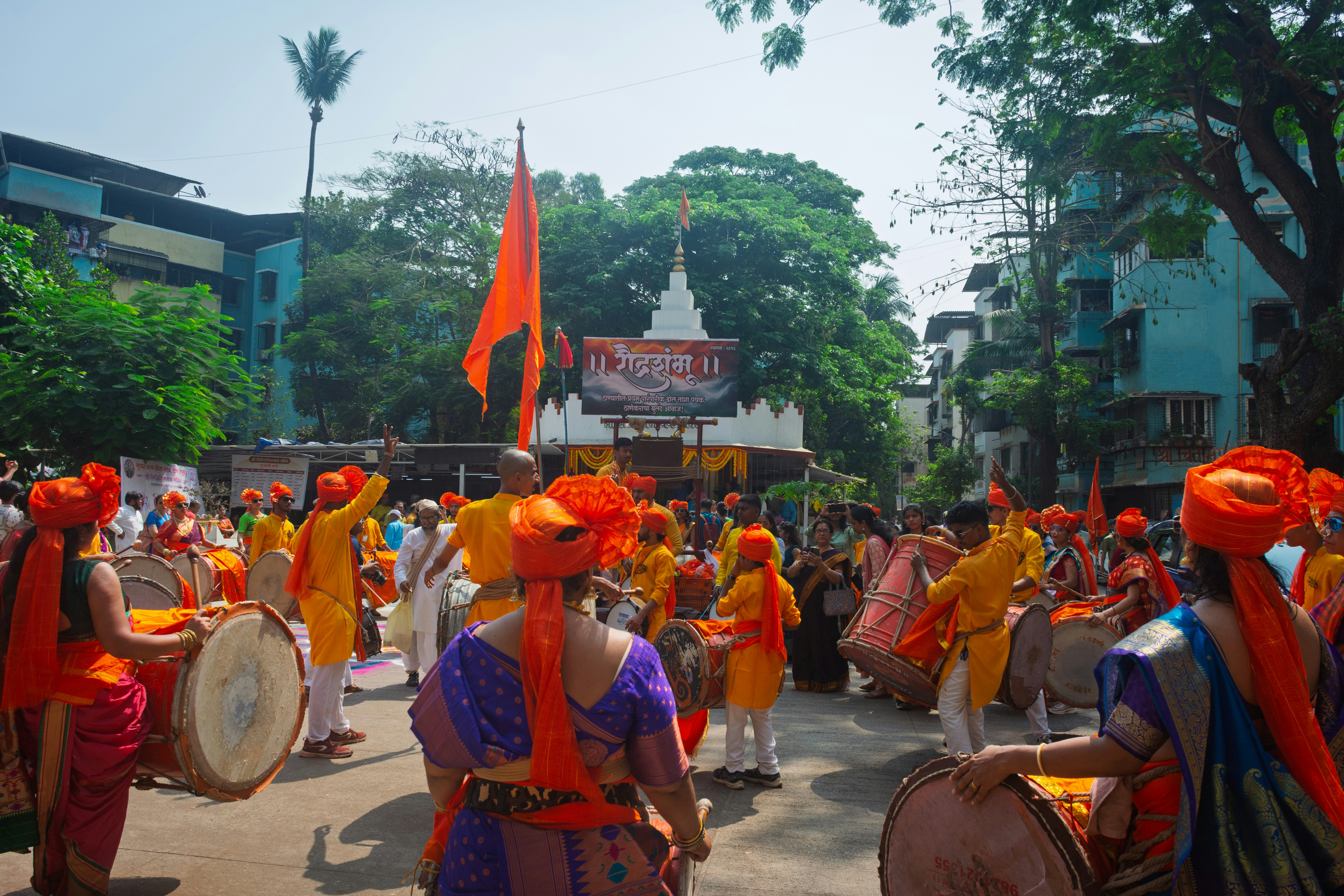 People in traditional attire marching with drums and flags.