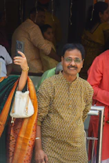 Man in traditional indian clothing smiling for a selfie.