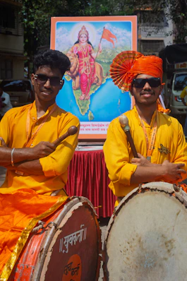 Two young men in traditional attire with drums.
