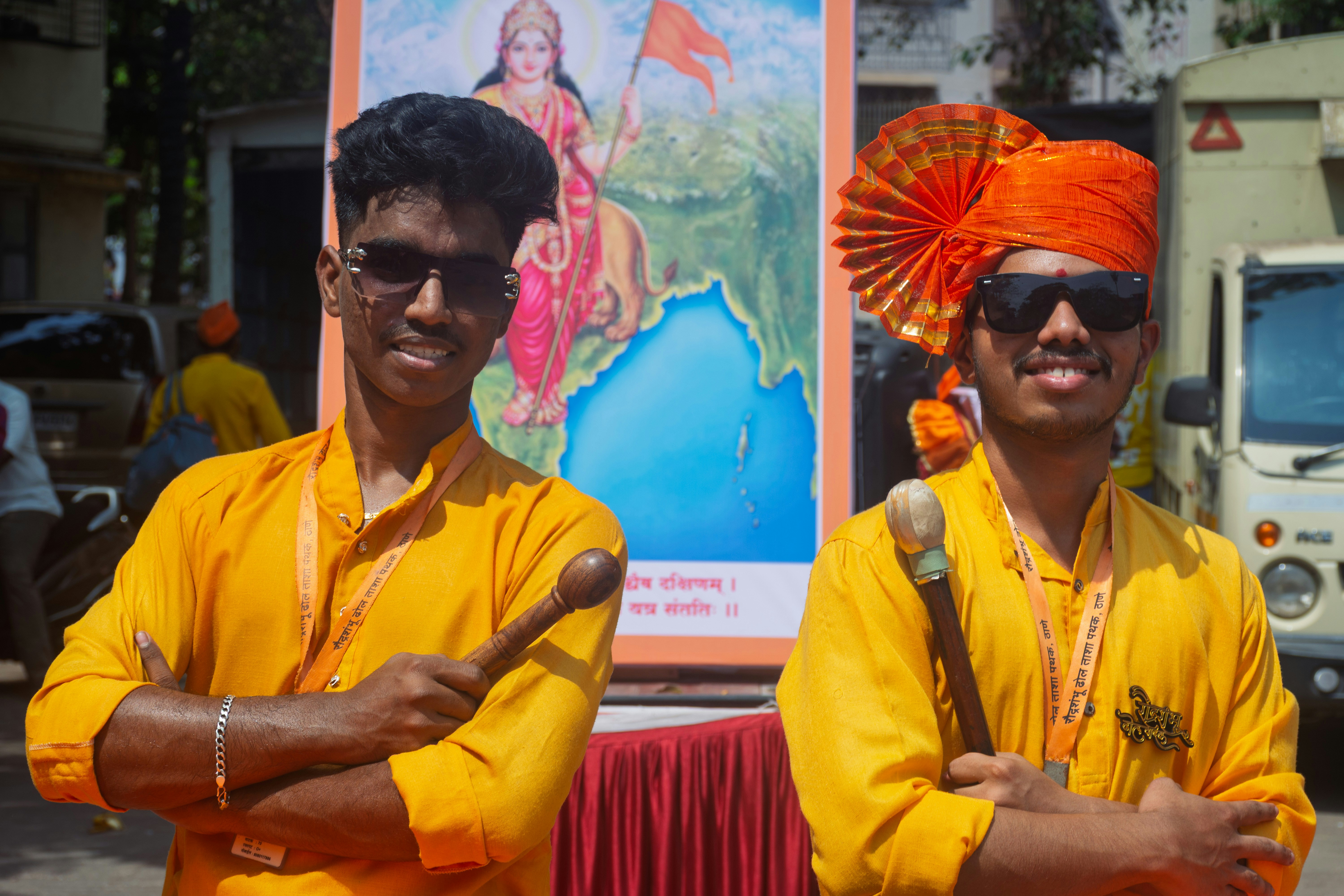 Two young men in orange outfits with drums