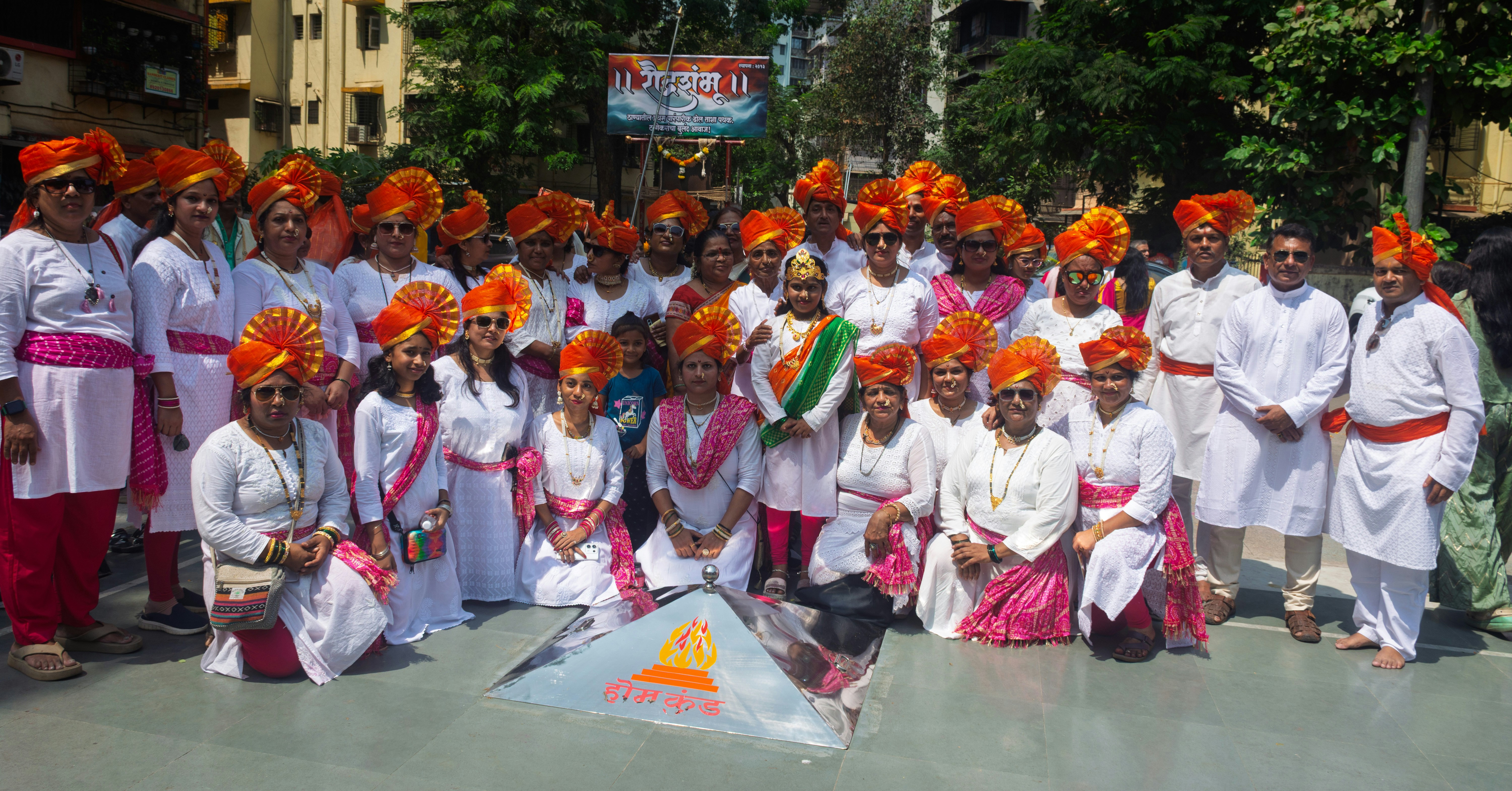 A group of people in traditional attire with orange turbans.