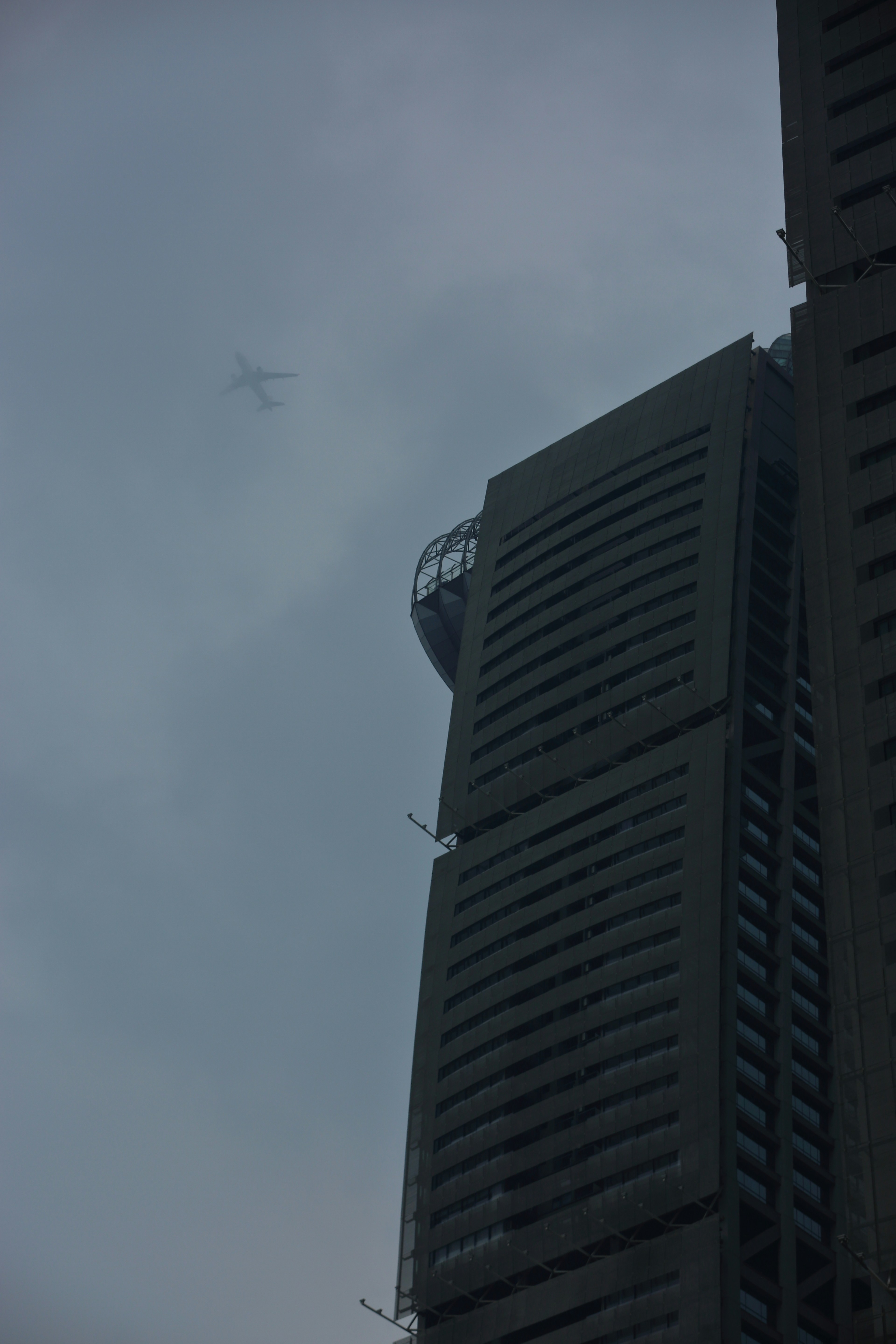 Um avião passa por um prédio alto em um dia nublado.