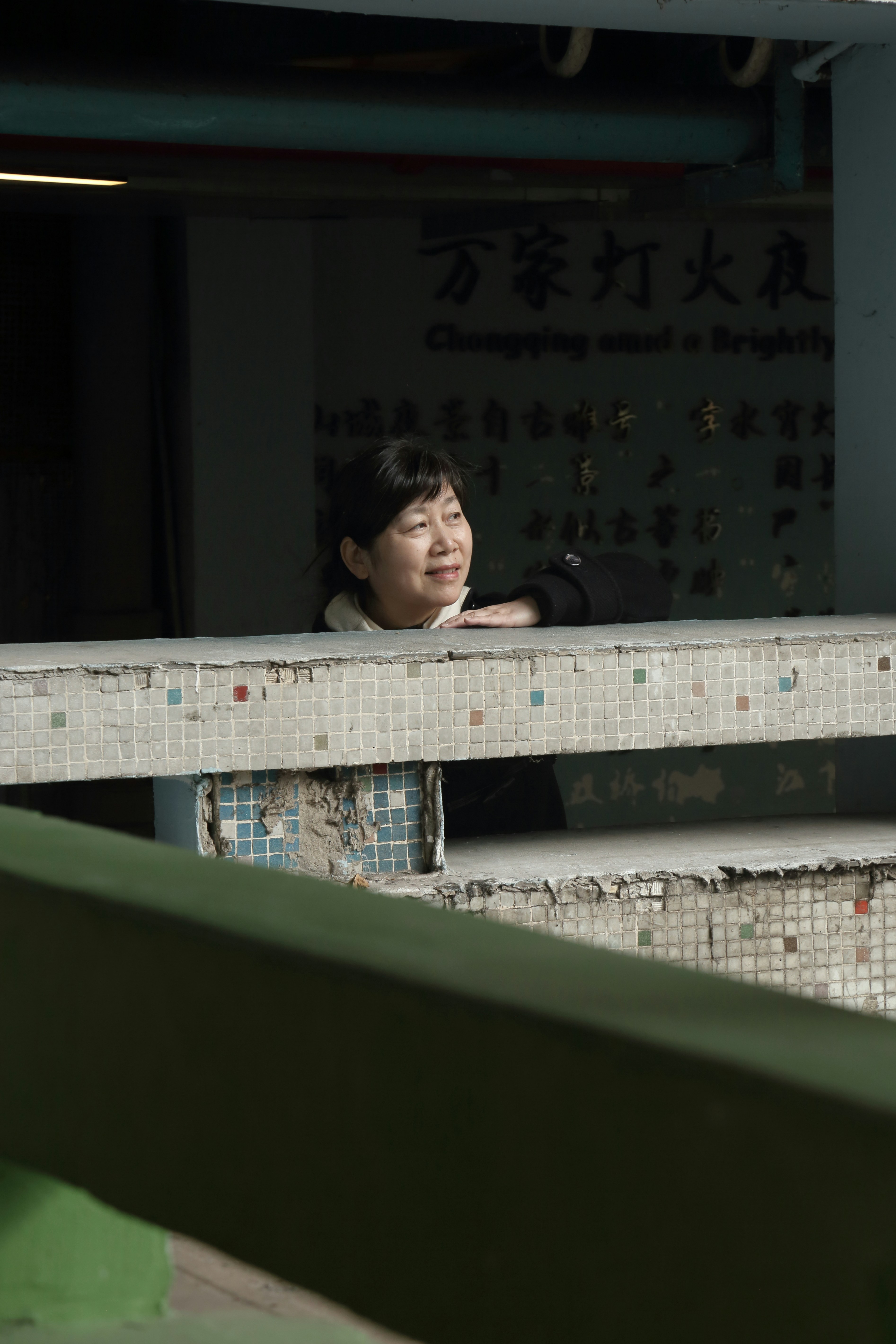 An asian woman peeks over a tiled ledge